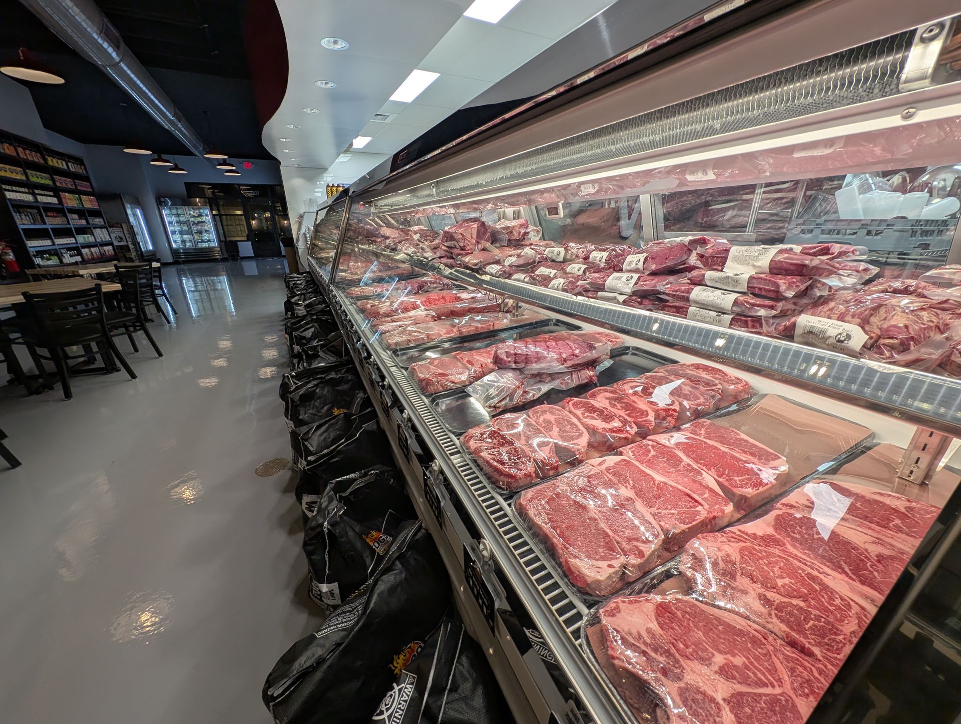 Supermarket meat display case filled with packaged red meat under bright lights
