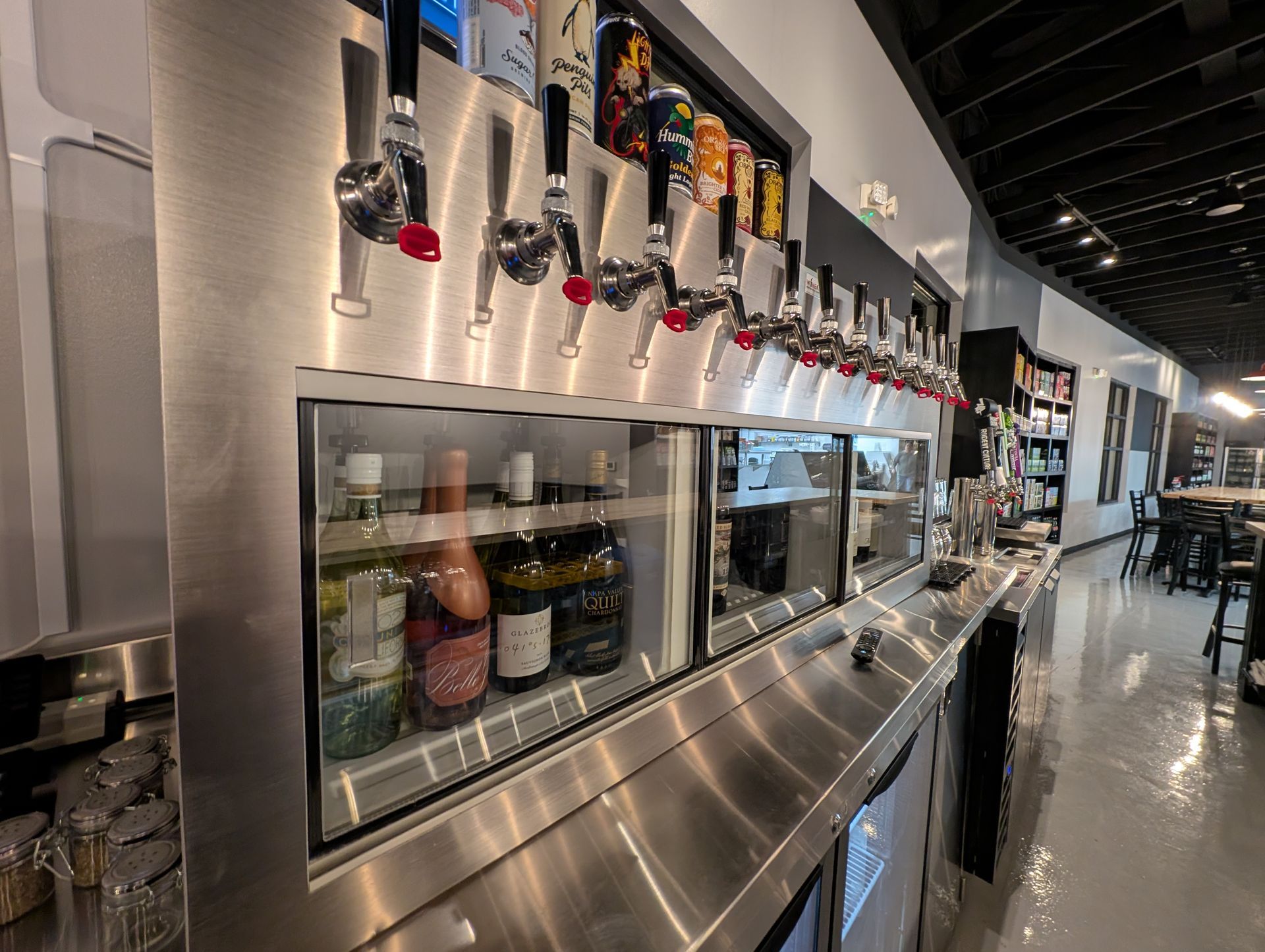 A row of beer taps above a glass-front refrigerated display in a sleek bar interior