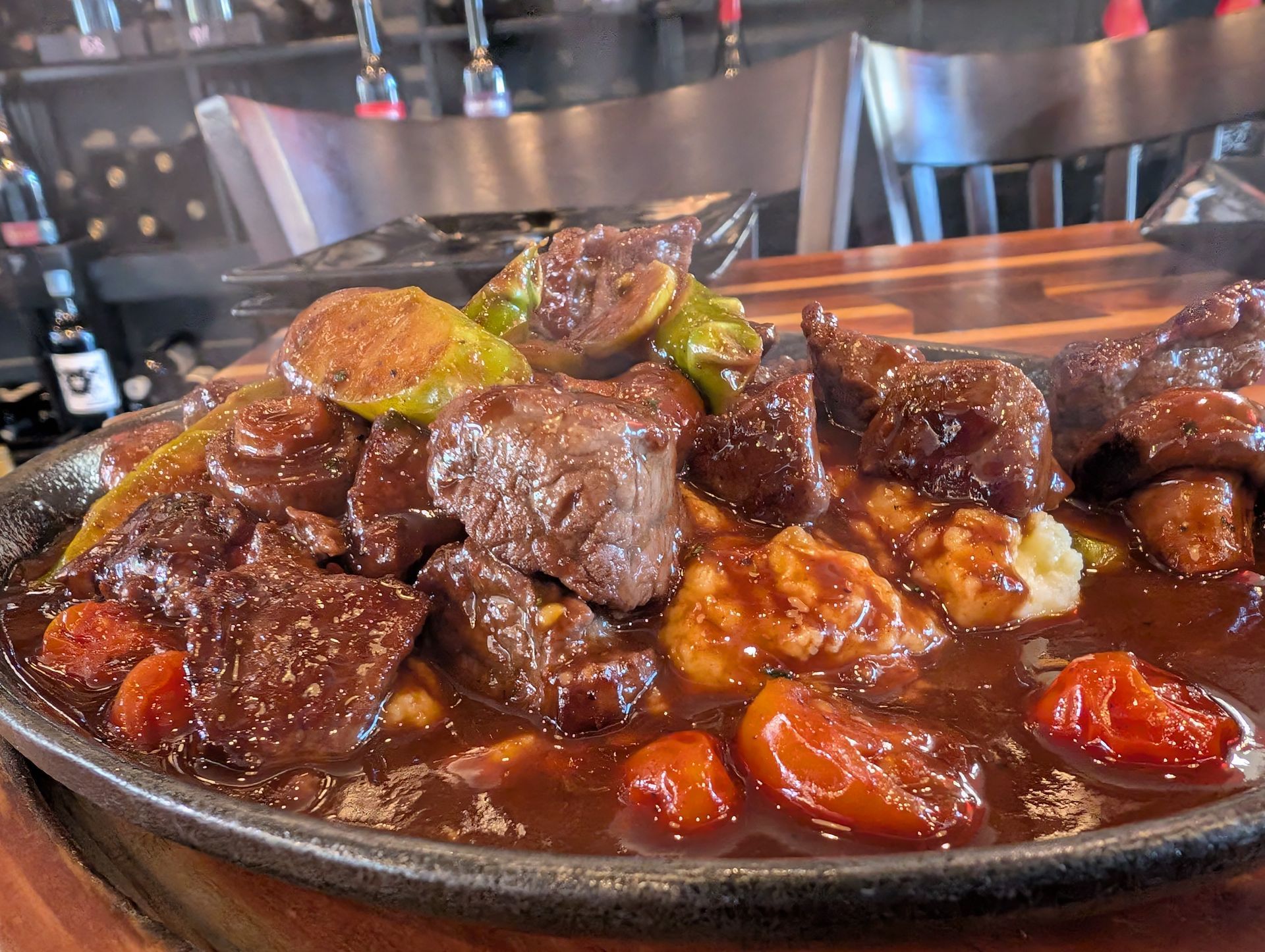 Braised beef in rich brown gravy with carrots on a plate at a restaurant counter
