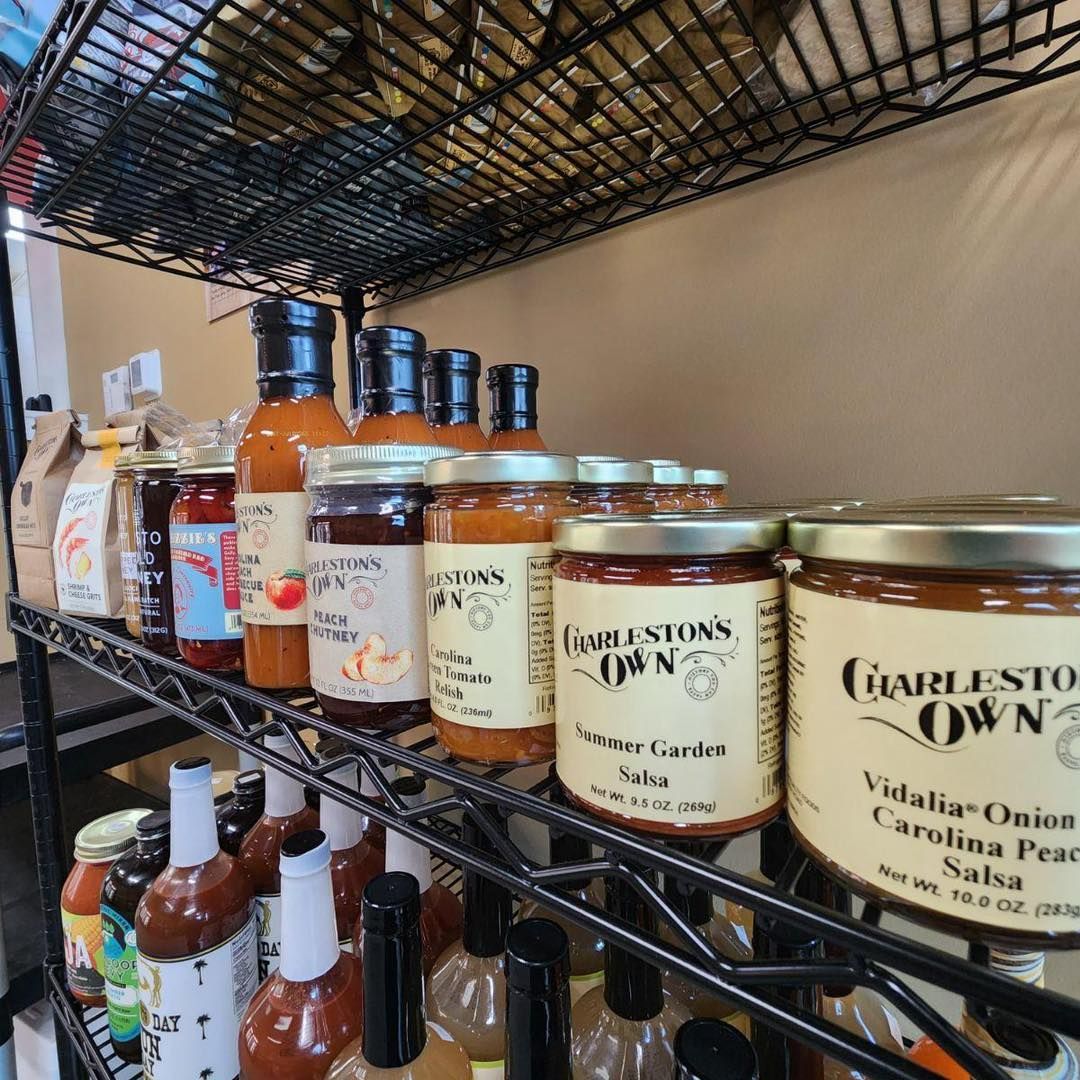 Shelves stocked with various Charleston Own salsa and hot sauce jars and bottles.