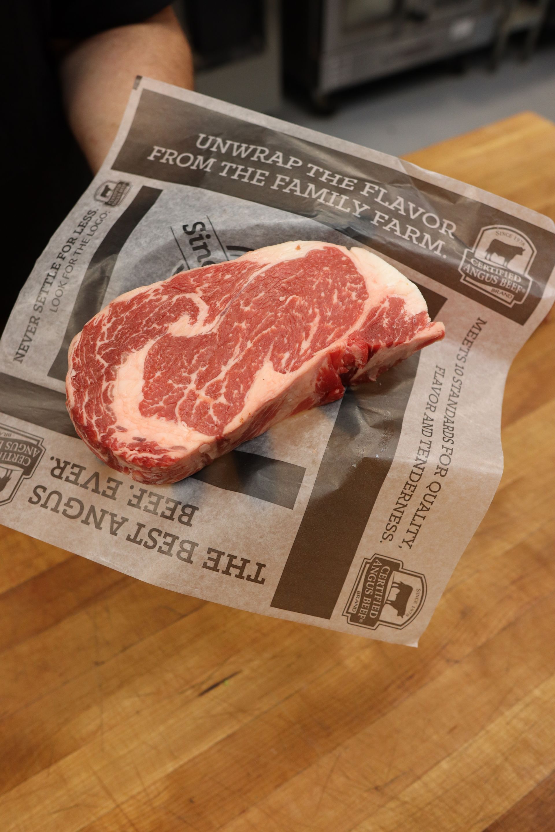 Raw marbled steak on butcher paper atop a wooden cutting board