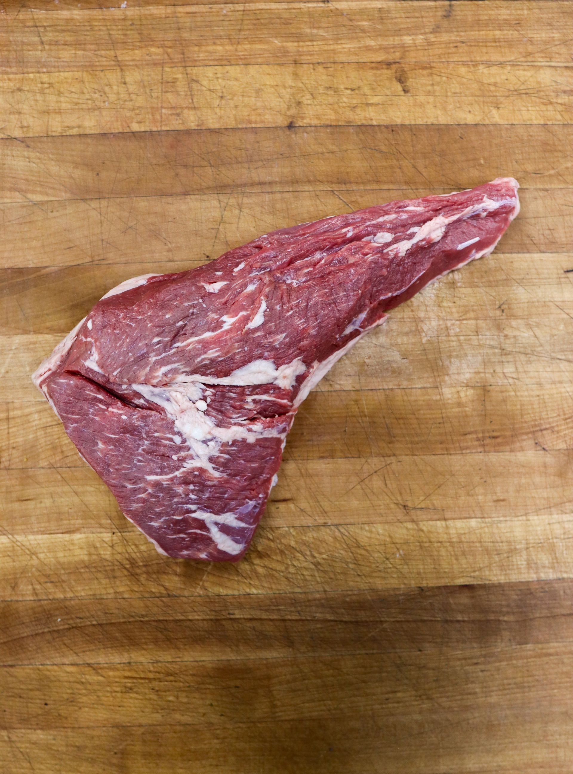 Raw red steak on a wooden cutting board.