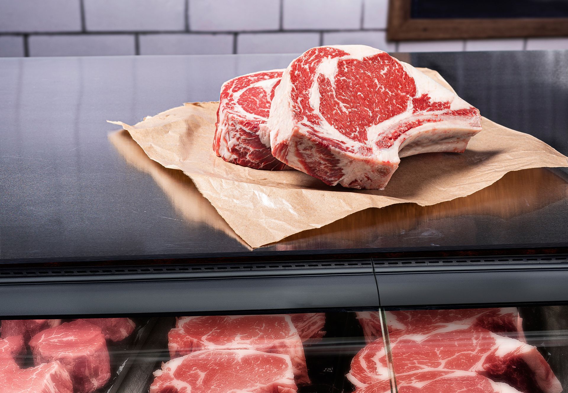 Raw marbled steaks on butcher paper in a refrigerated meat display case