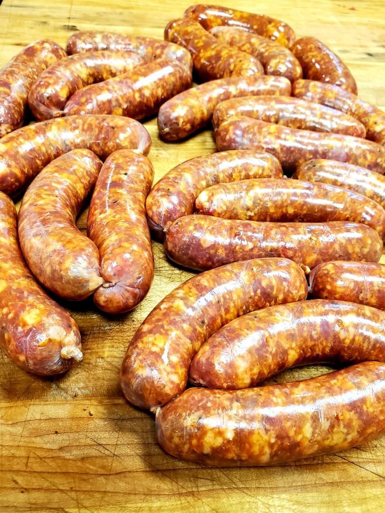 Freshly made sausages on a wooden cutting board, reddish-brown in color.