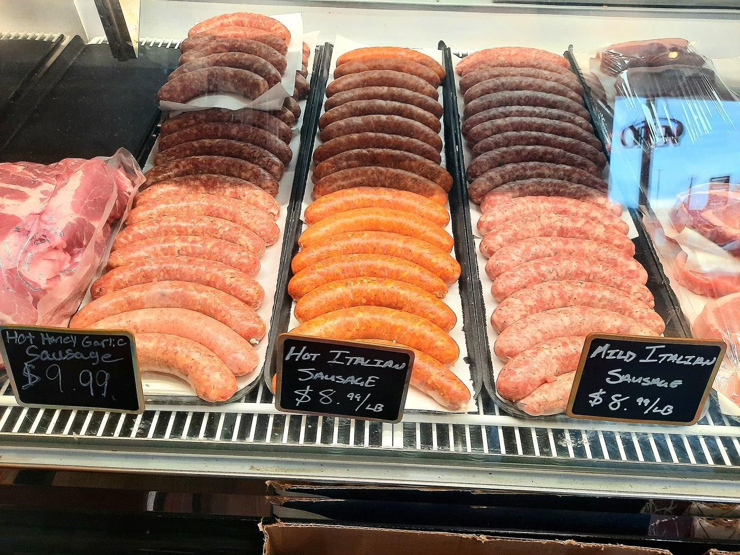 Sausage display case with rows of various sausages. Labels indicate