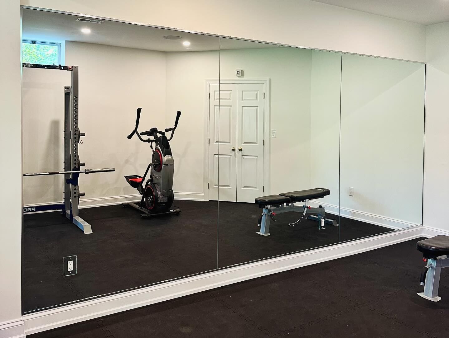 A gym with a large mirror on the wall and a bench.