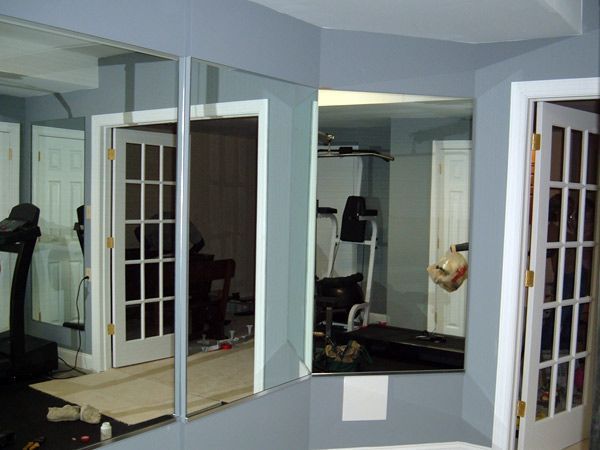 A room with a treadmill and mirrors on the wall