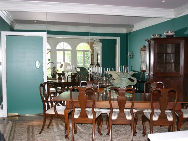 A dining room with a table and chairs and green walls