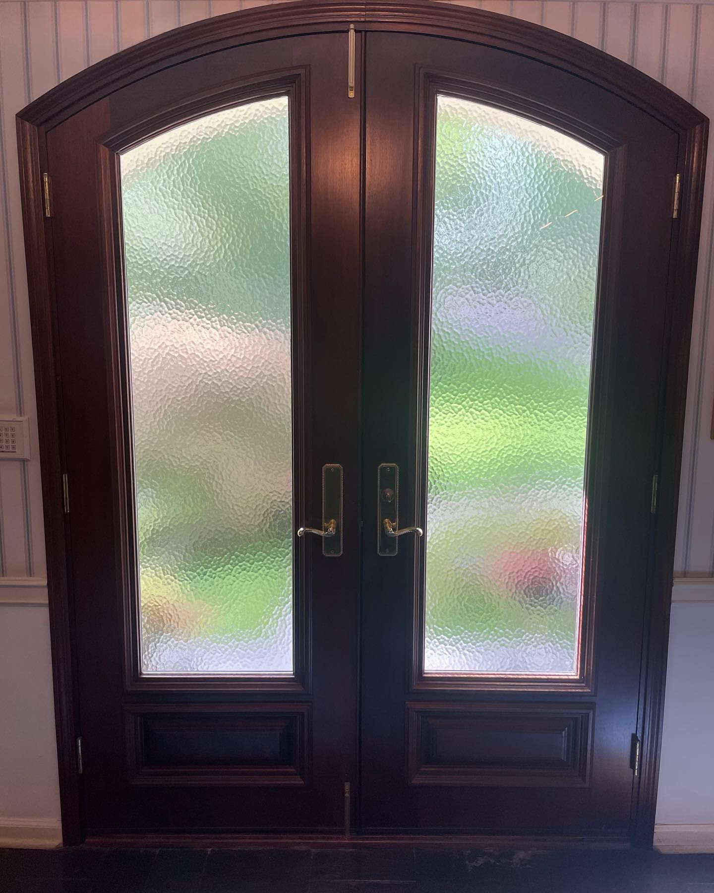 A pair of arched glass doors with a stained glass window