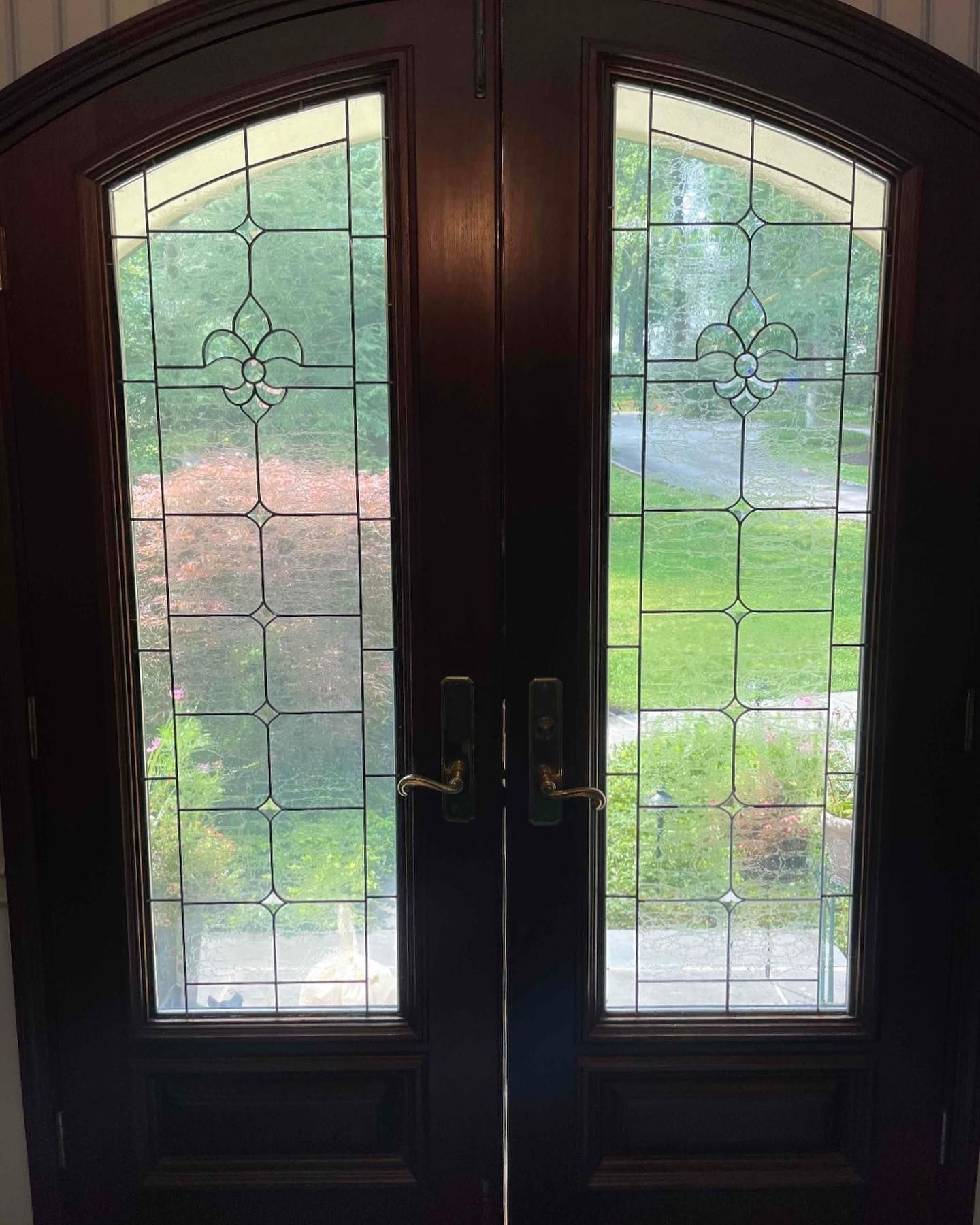 A pair of stained glass doors with a view of a yard.