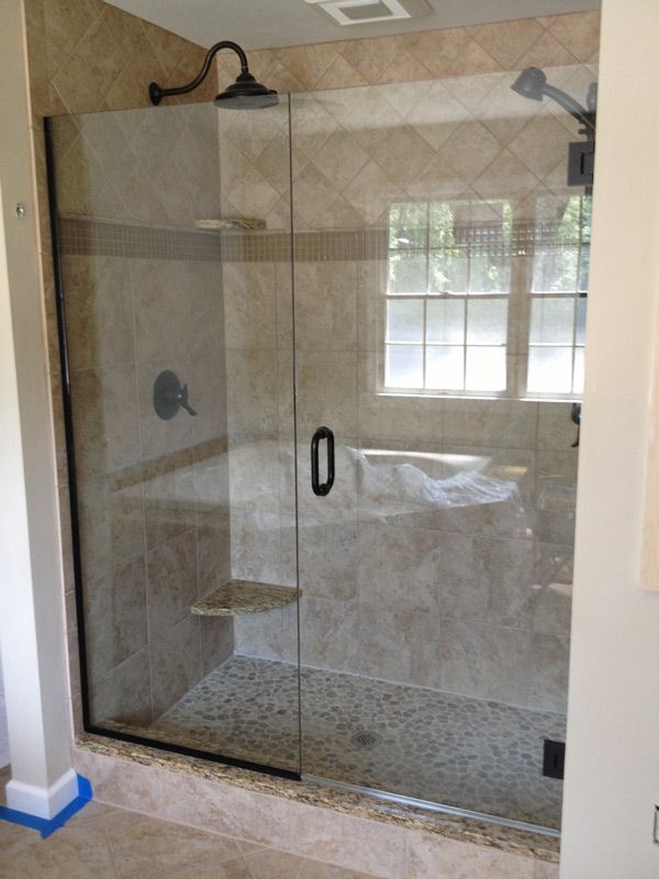 A bathroom with a glass shower door and a window