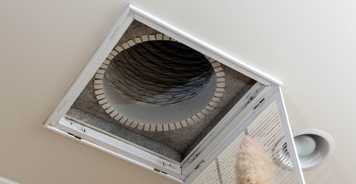Open attic access panel in ceiling with exposed ductwork inside