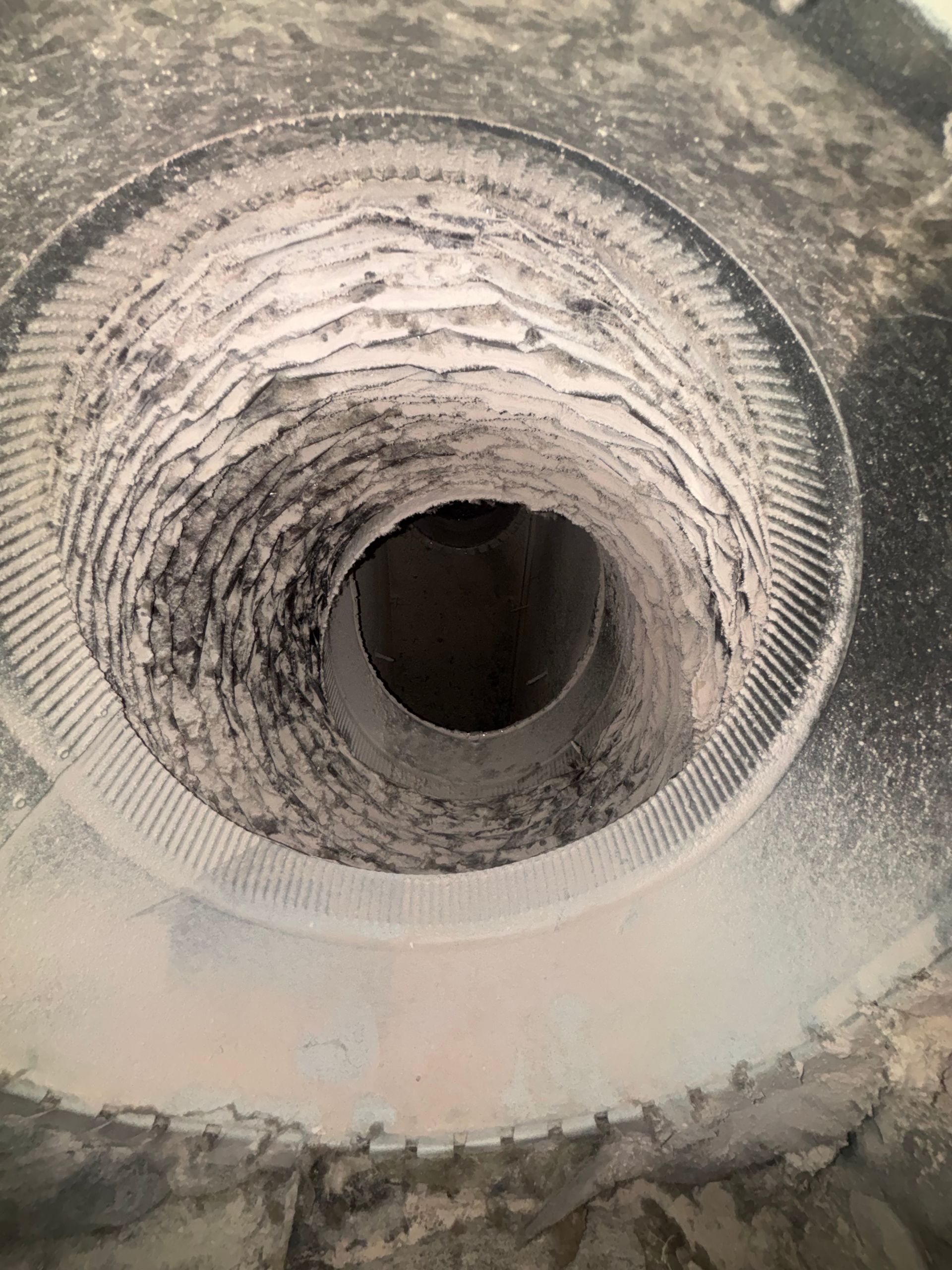 Close-up of a dusty, threaded metal pipe opening with a circular bore.