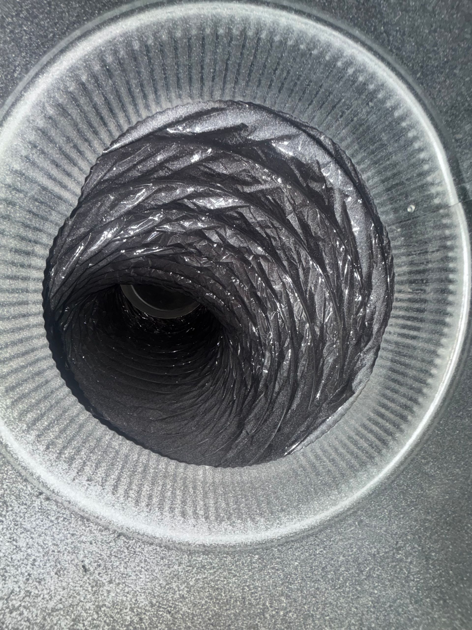 Close-up of a gray corrugated hose opening with a dark circular center