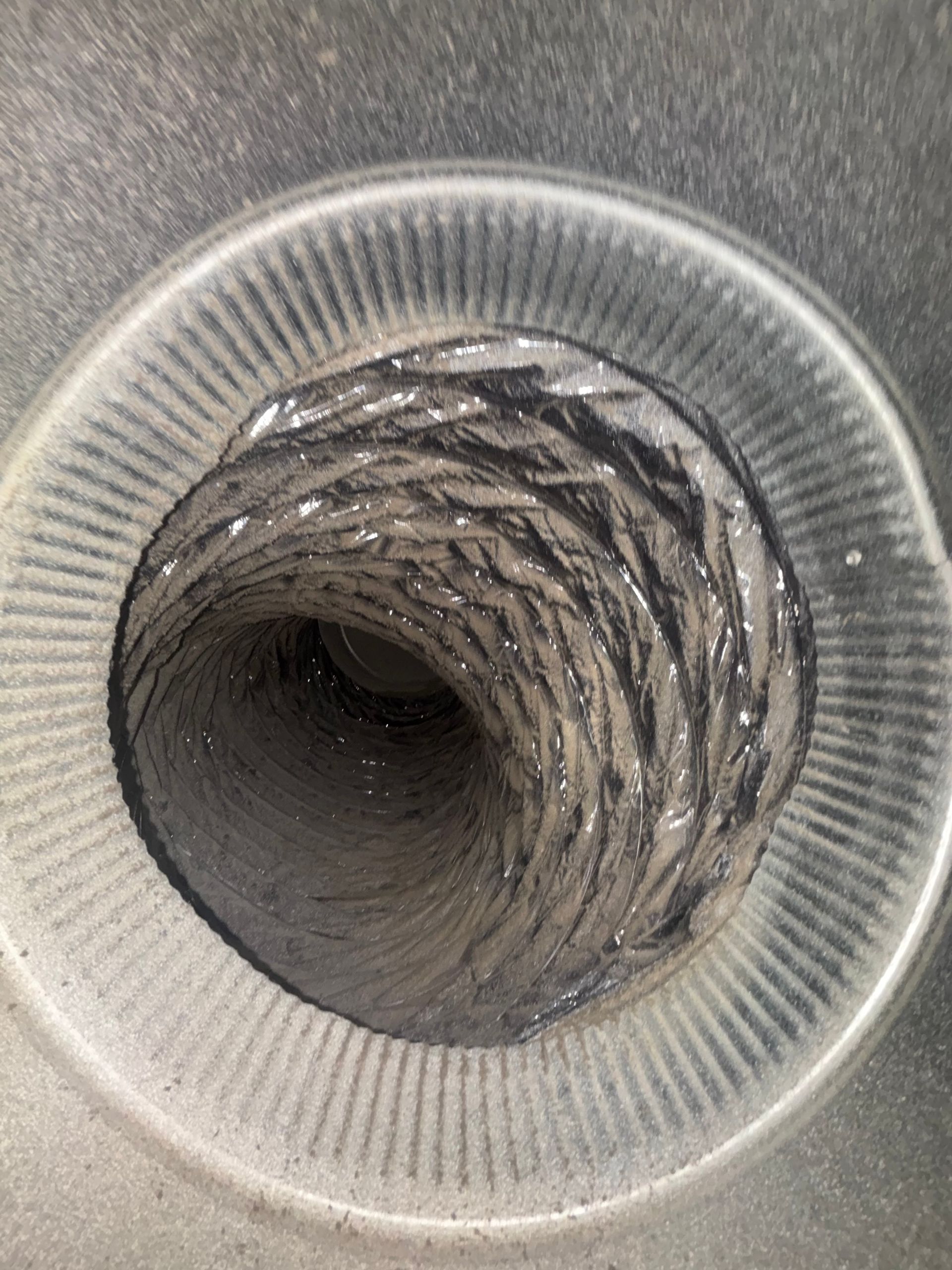 Close-up view looking down a ribbed metallic pipe or tunnel opening.