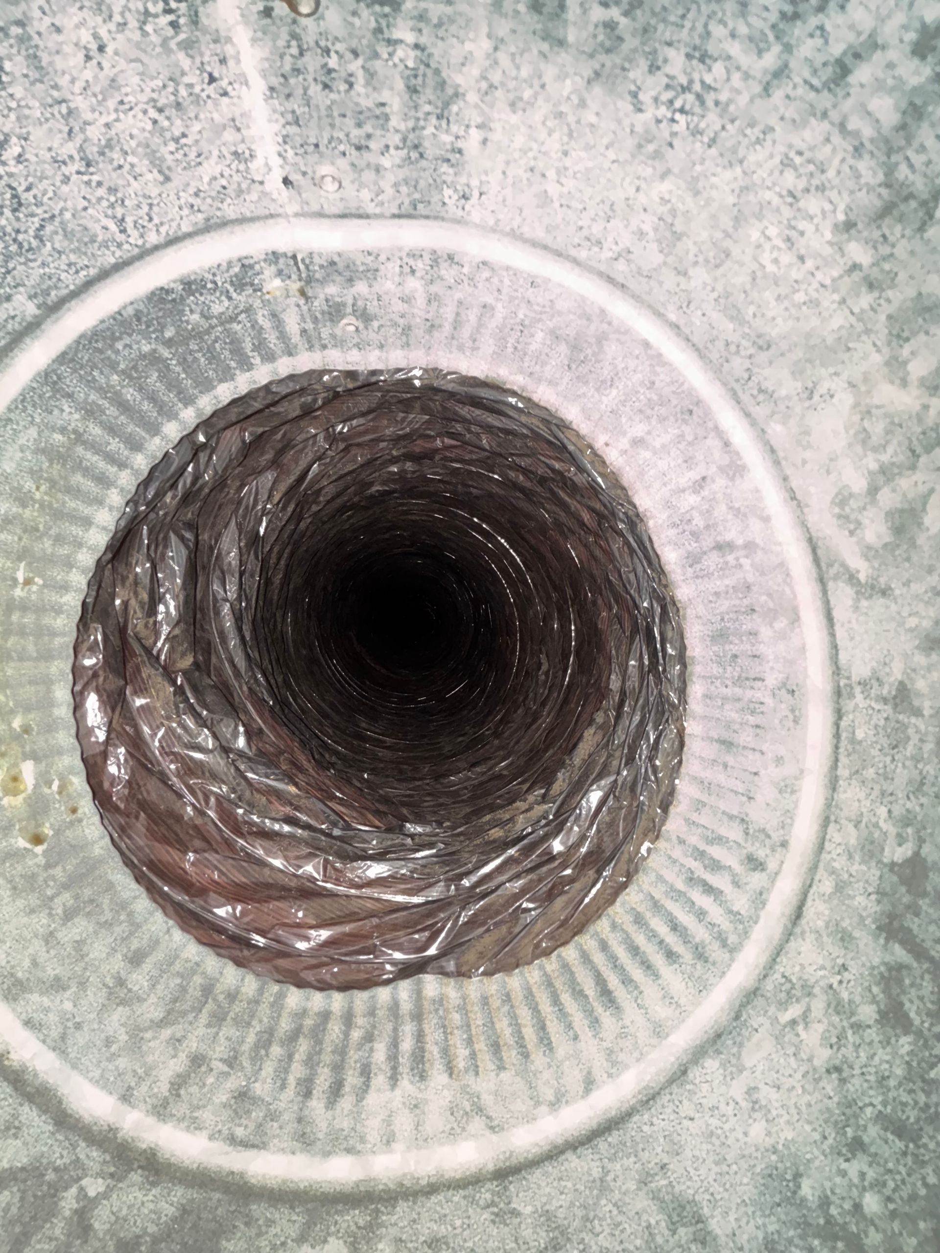 Close-up of a circular ventilation duct opening with a white grille and dark interior