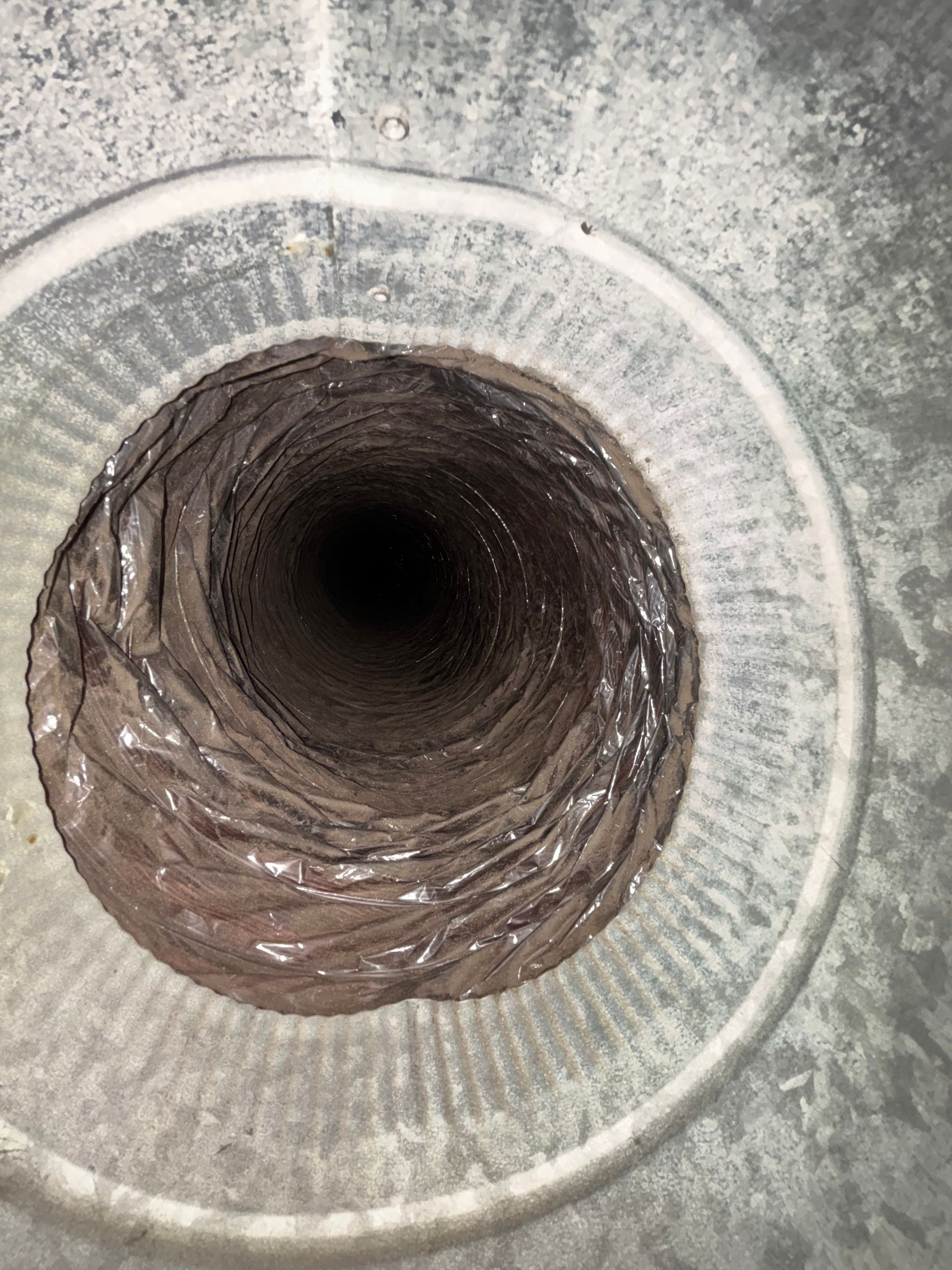 Circular vent or pipe opening with a dark tunnel interior and textured gray rim