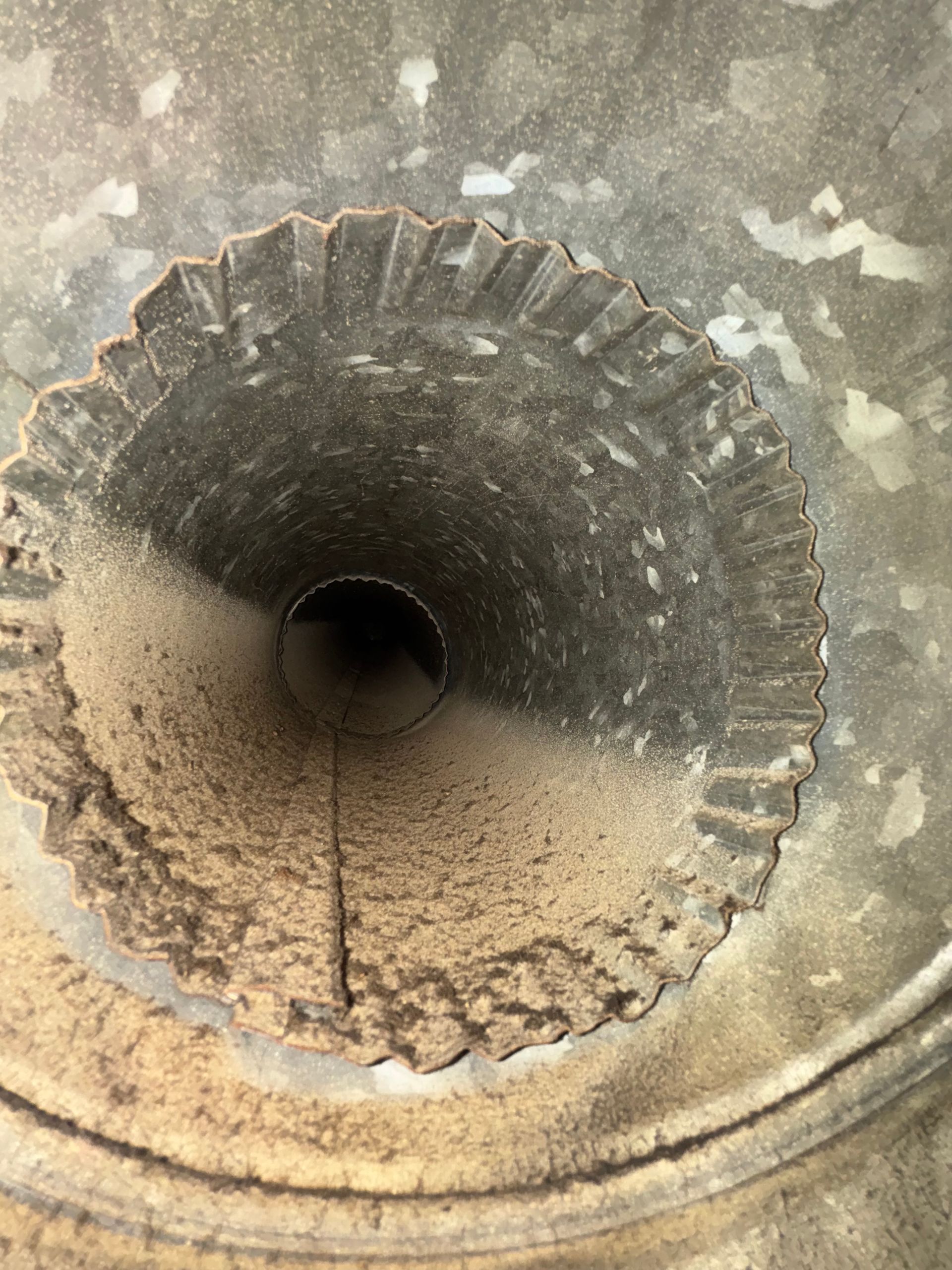 Close-up of a dusty circular concrete pipe with a dark opening and debris inside