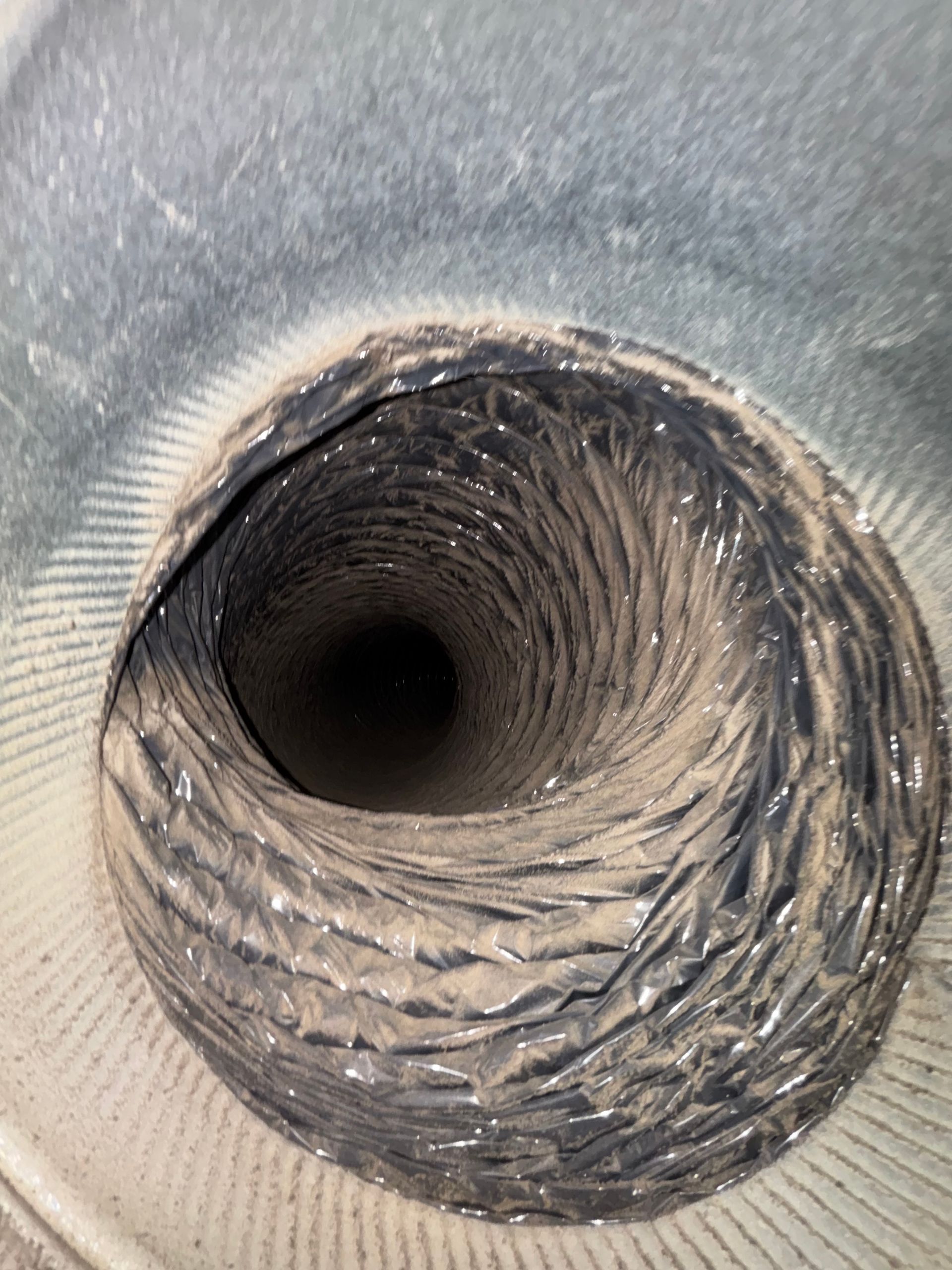 Close-up of a corrugated metal duct interior with a dark circular opening