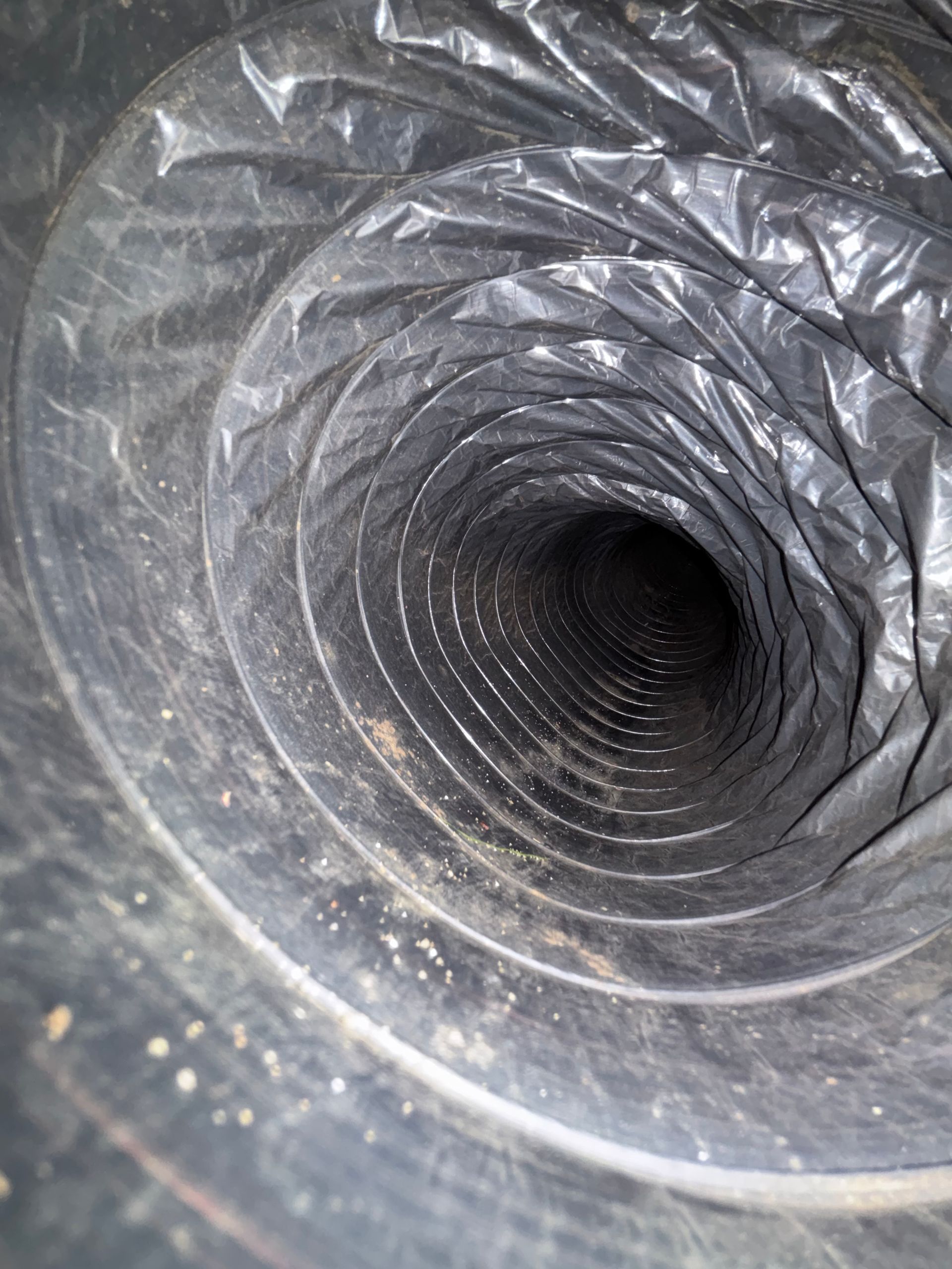 Inside a black corrugated tunnel or duct, viewed looking inward from one end
