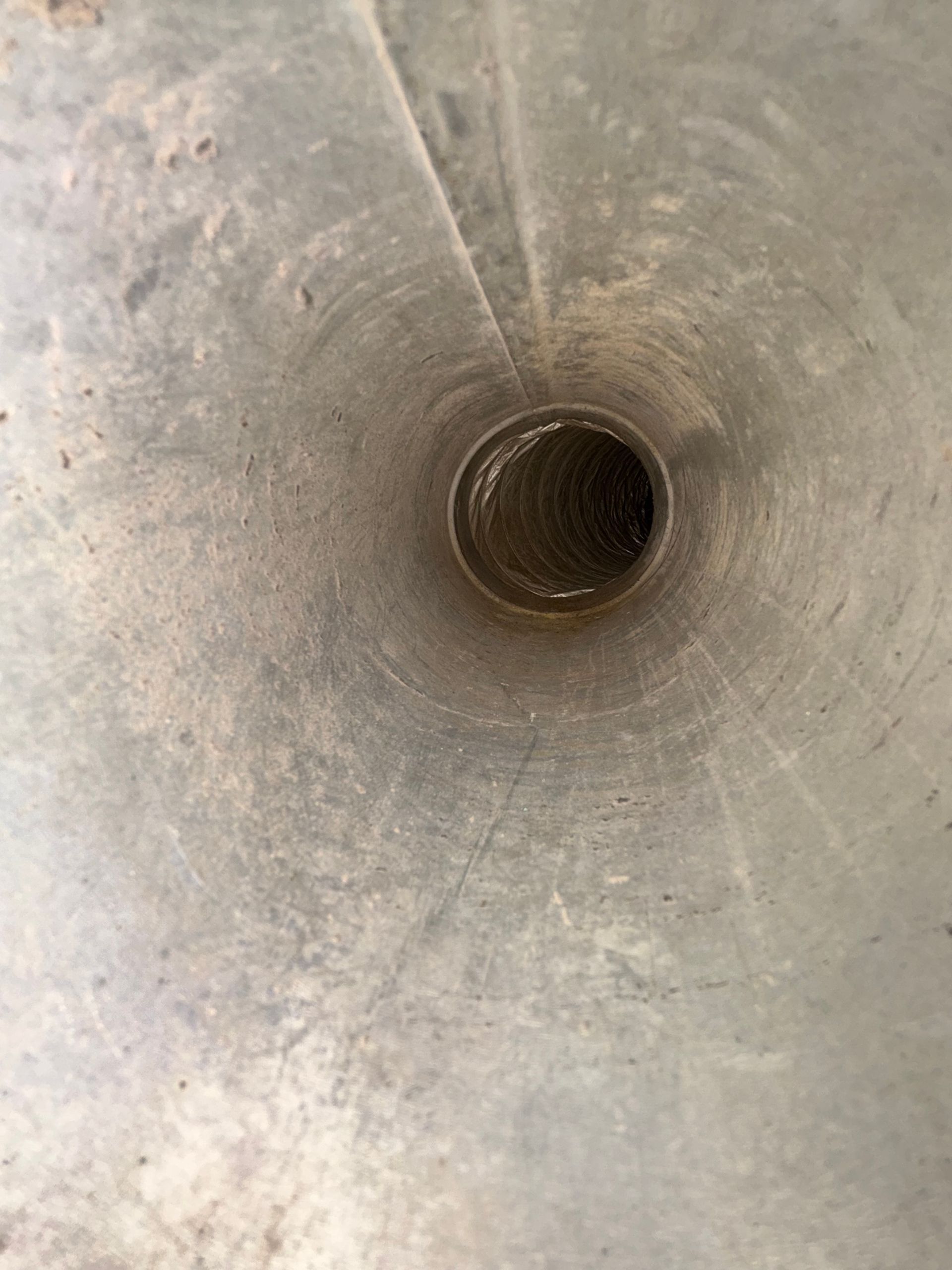 Close-up of a gray metal funnel with a small dark opening in the center