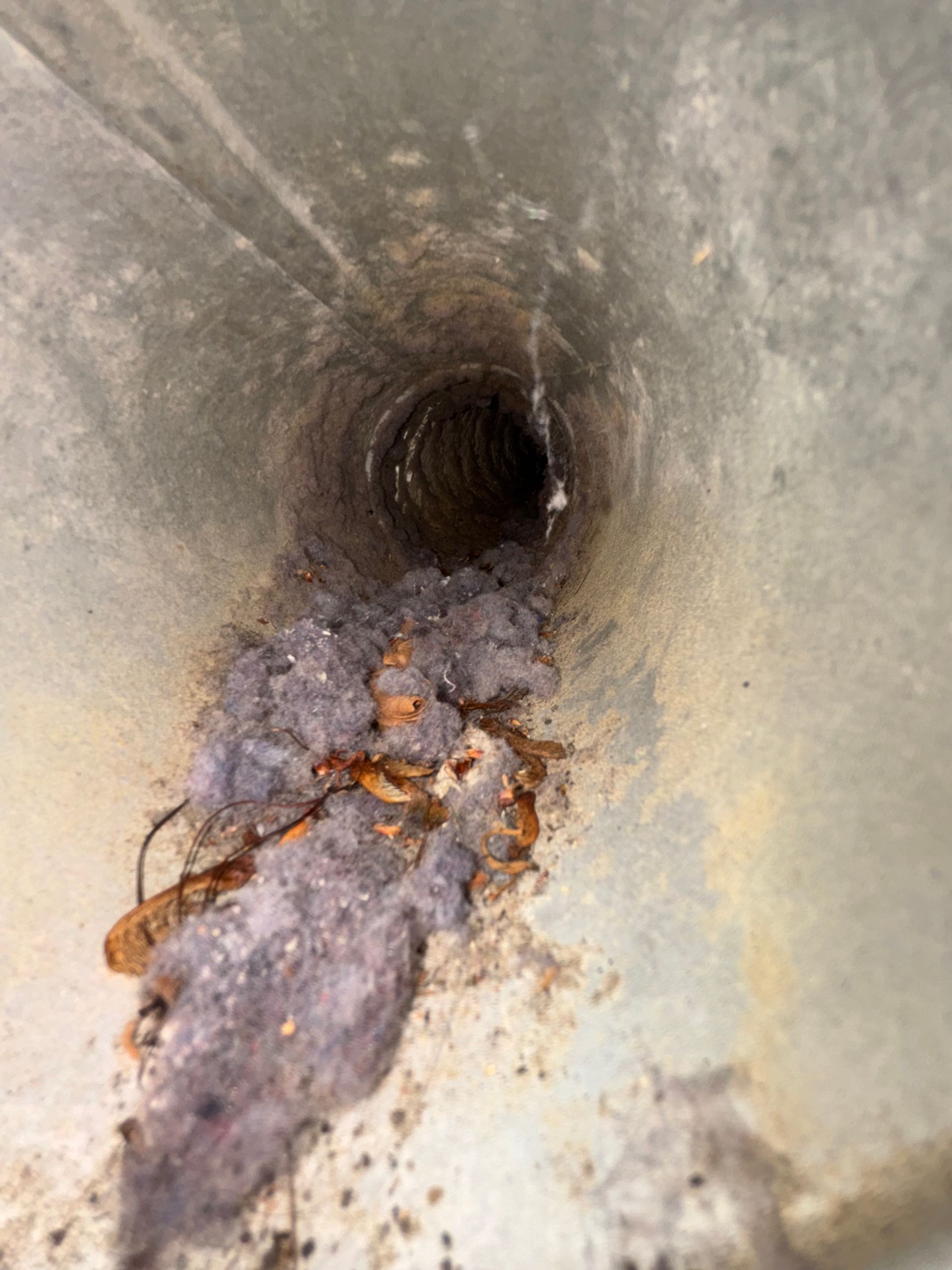 Clogged metal pipe with rust and debris buildup near the opening