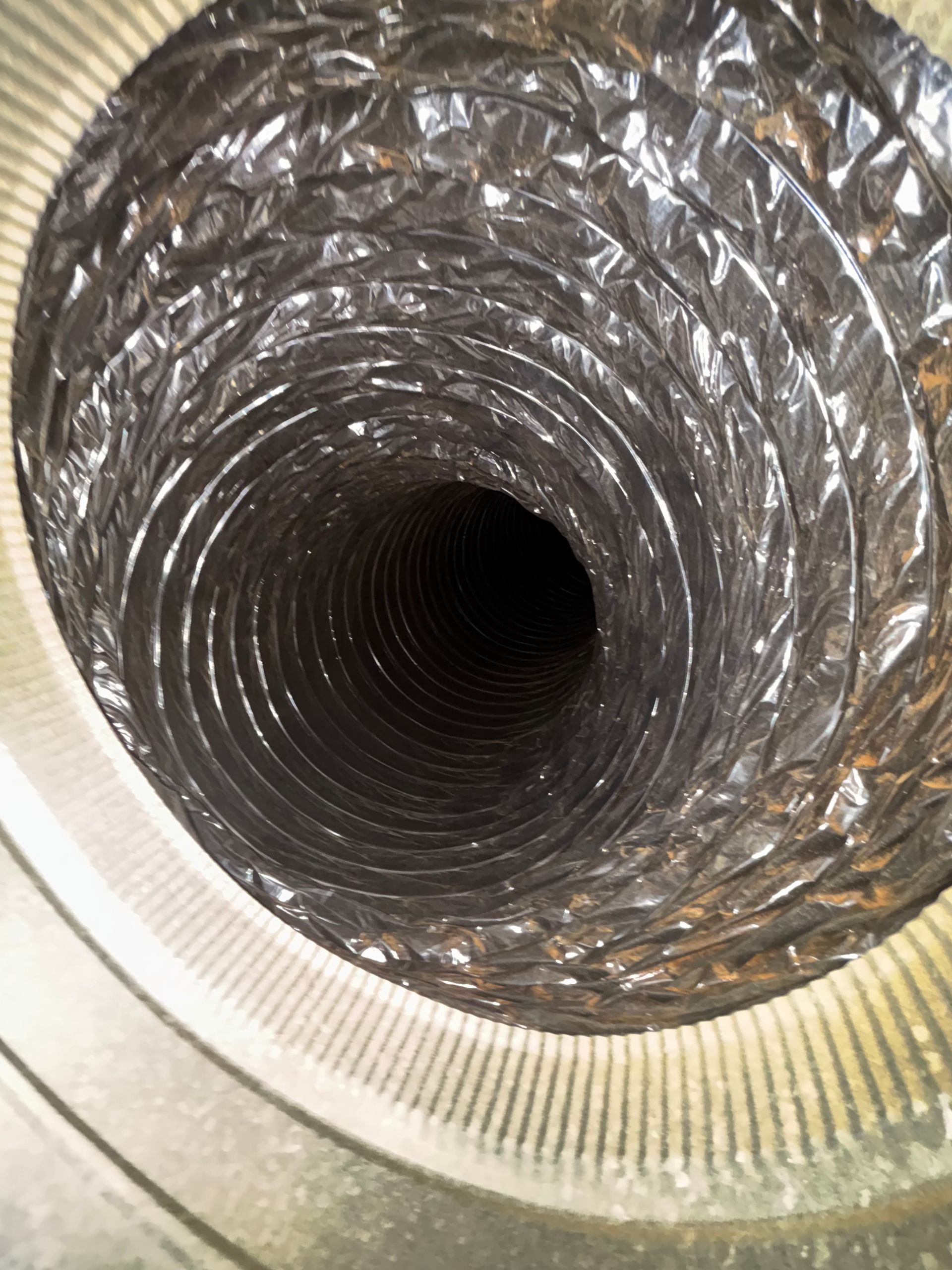 Looking down the inside of a metallic, flexible ventilation duct or pipe