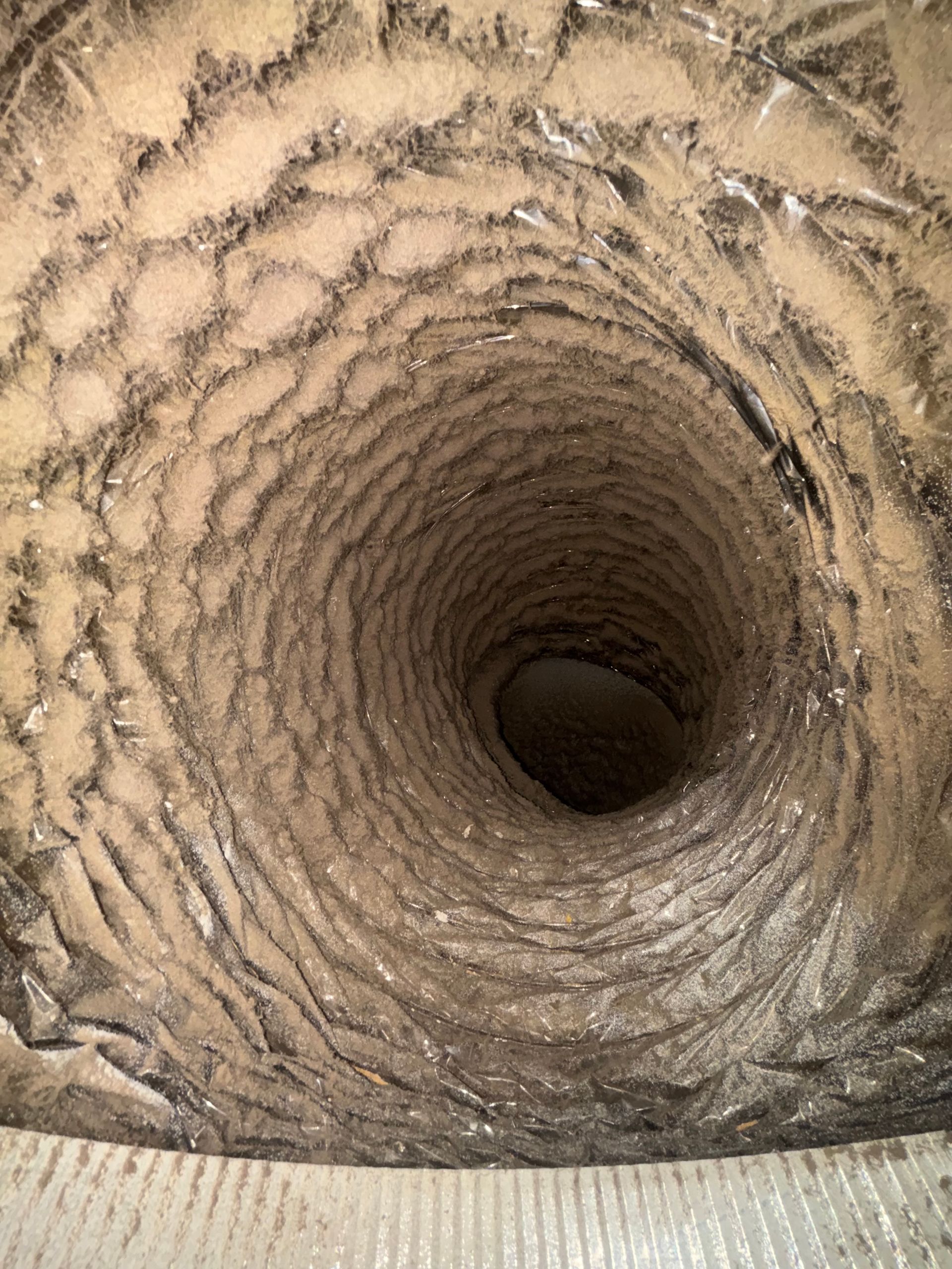 Close-up of a spiraling muddy tunnel or borehole with rough, textured walls.