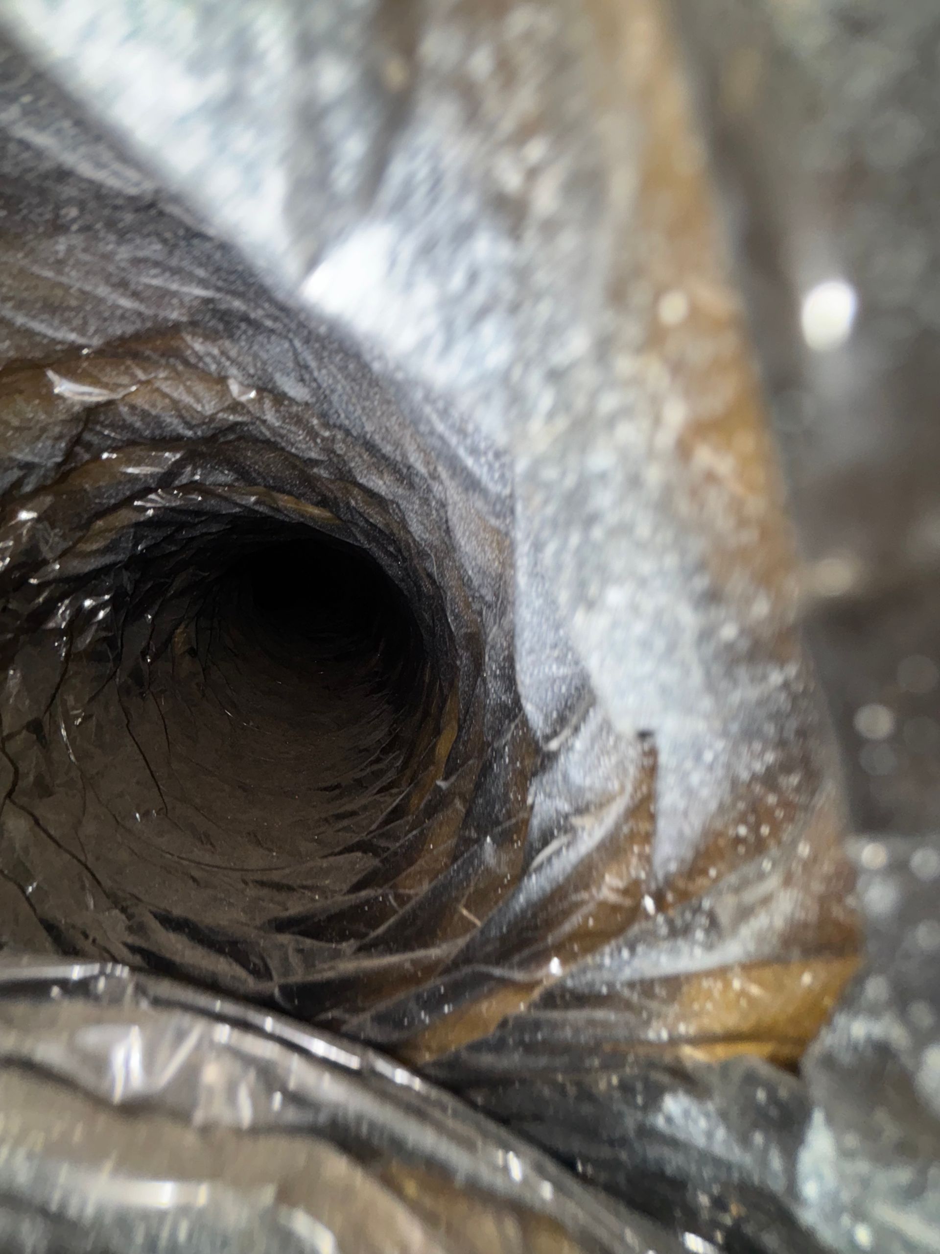 Close-up of a dark hollow inside crumpled silver-gray plastic or foil.