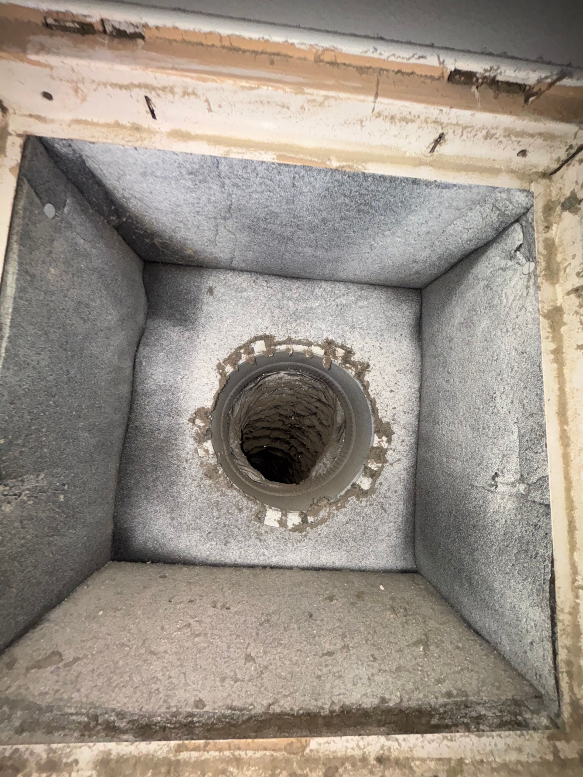 Square concrete opening with a central round pipe hole, viewed from above