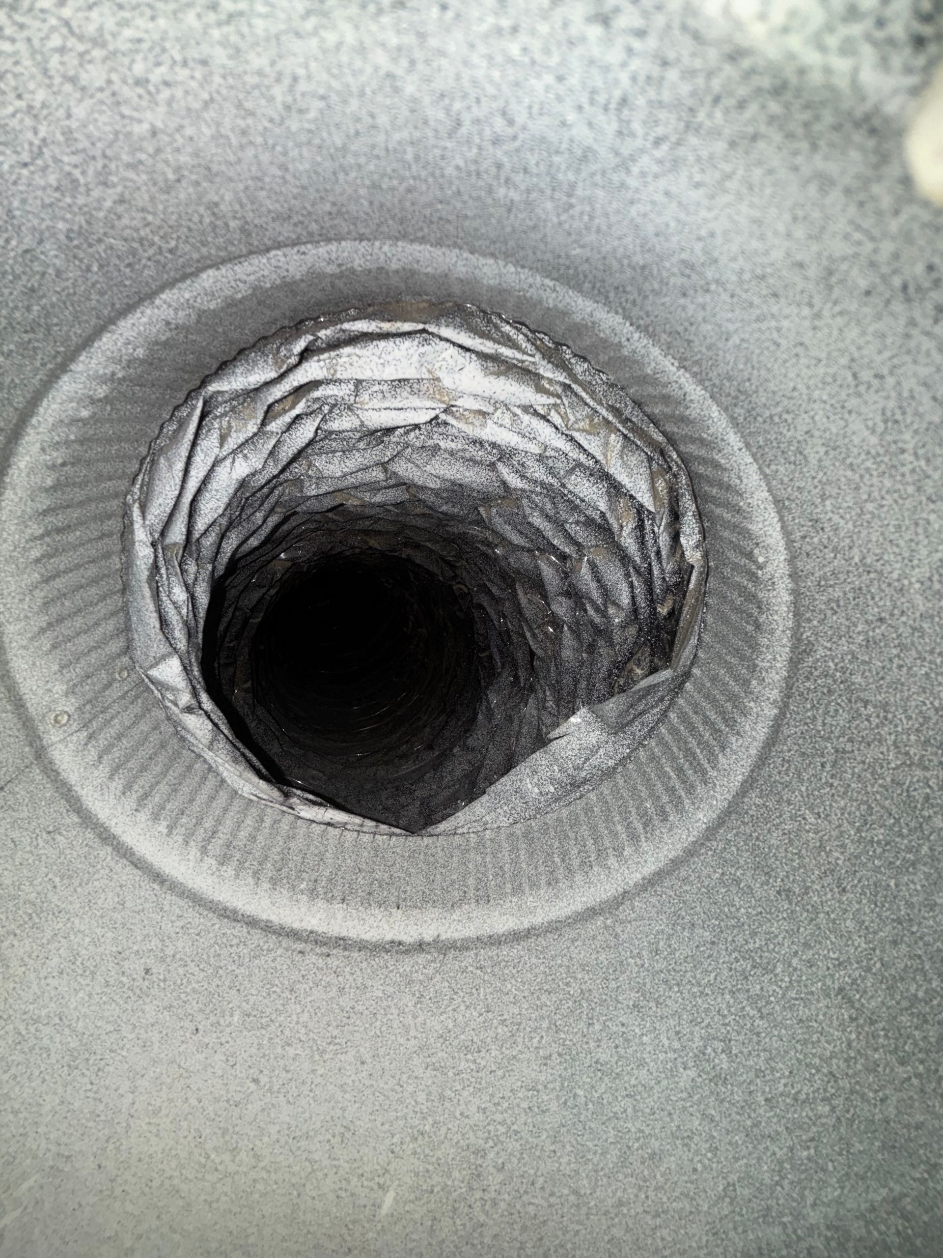 Close-up of a circular hole in a gray textured surface, with a dark opening at the center