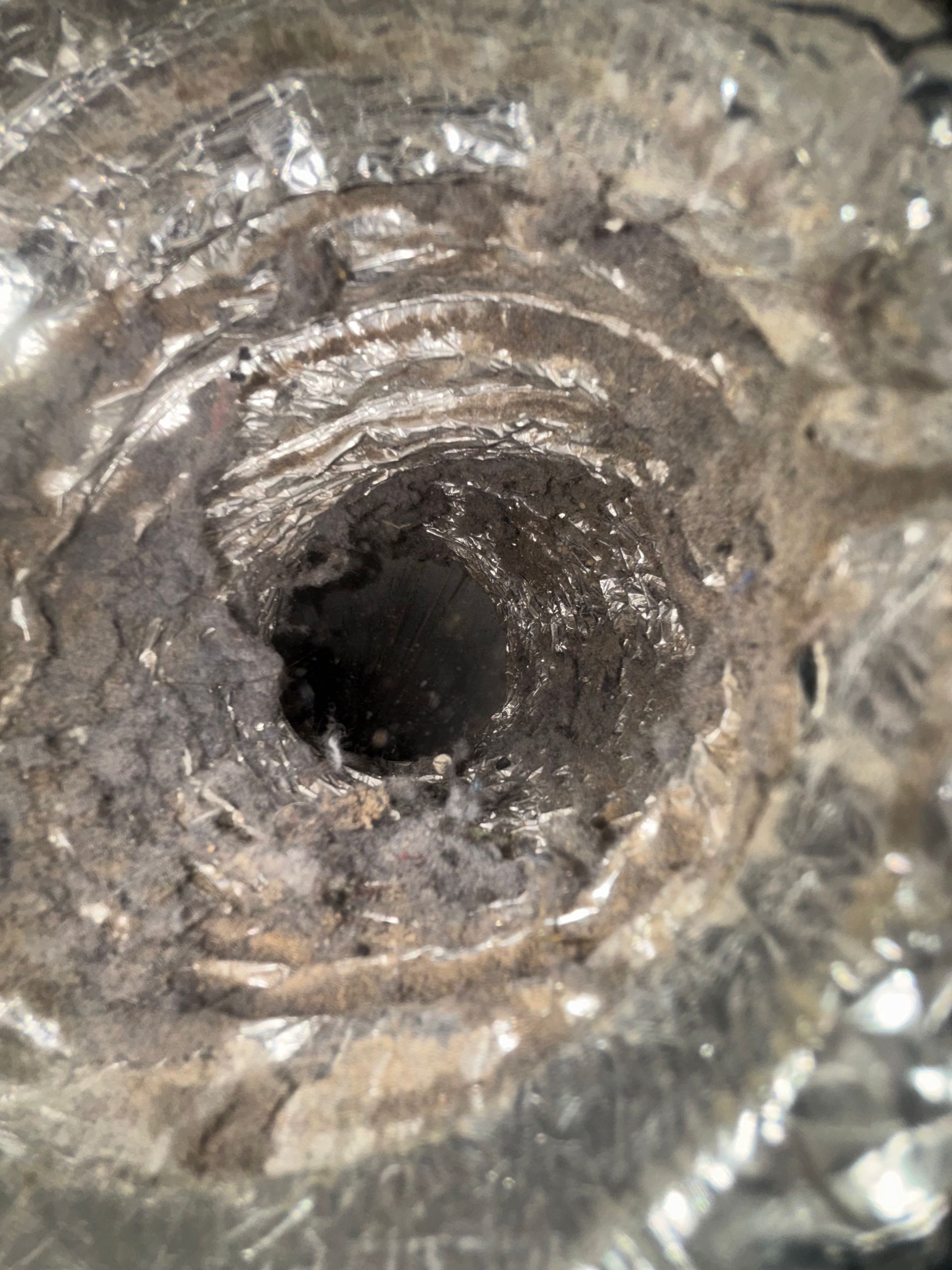 Close-up of a rusted metal hole with concentric grooves and a dark center