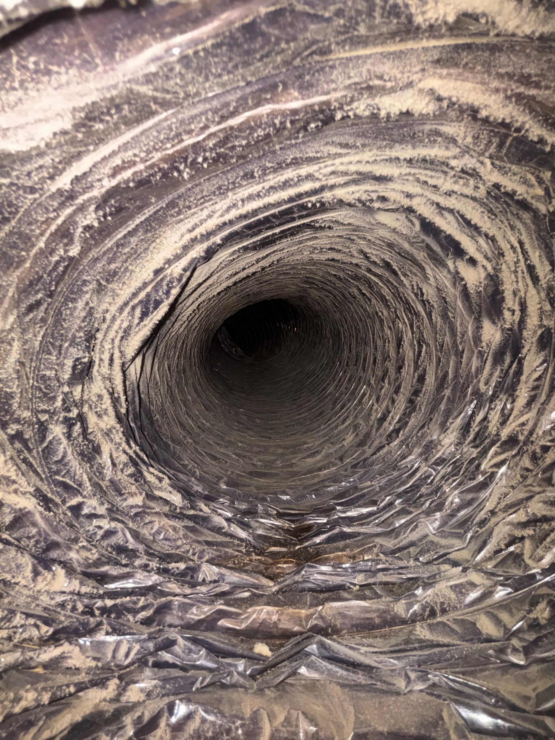 Close-up of a rough, gray tunnel or pipe interior with a dark opening in the center