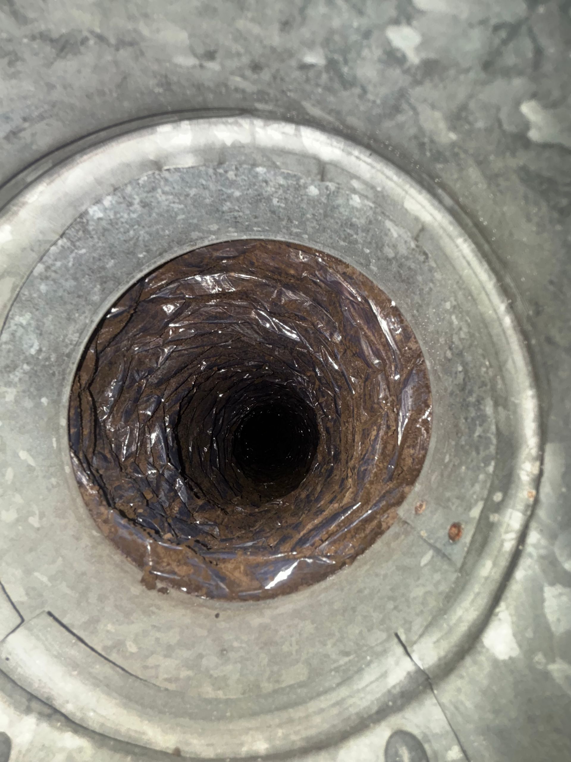Close-up of a rusty cylindrical pipe opening in a concrete surface