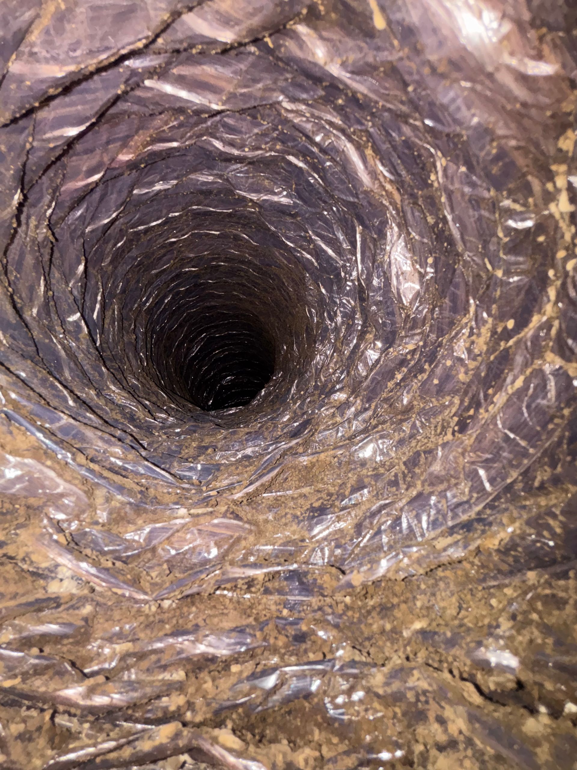 Inside a cylindrical tunnel, a dark circular opening recedes into a metallic, textured surface.