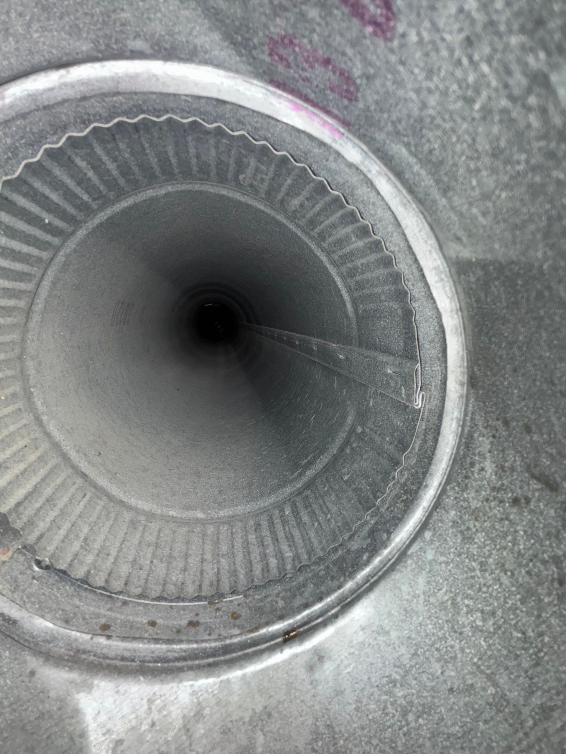 Close-up of a circular metallic vent or speaker grille with a dark center and ridged inner ring
