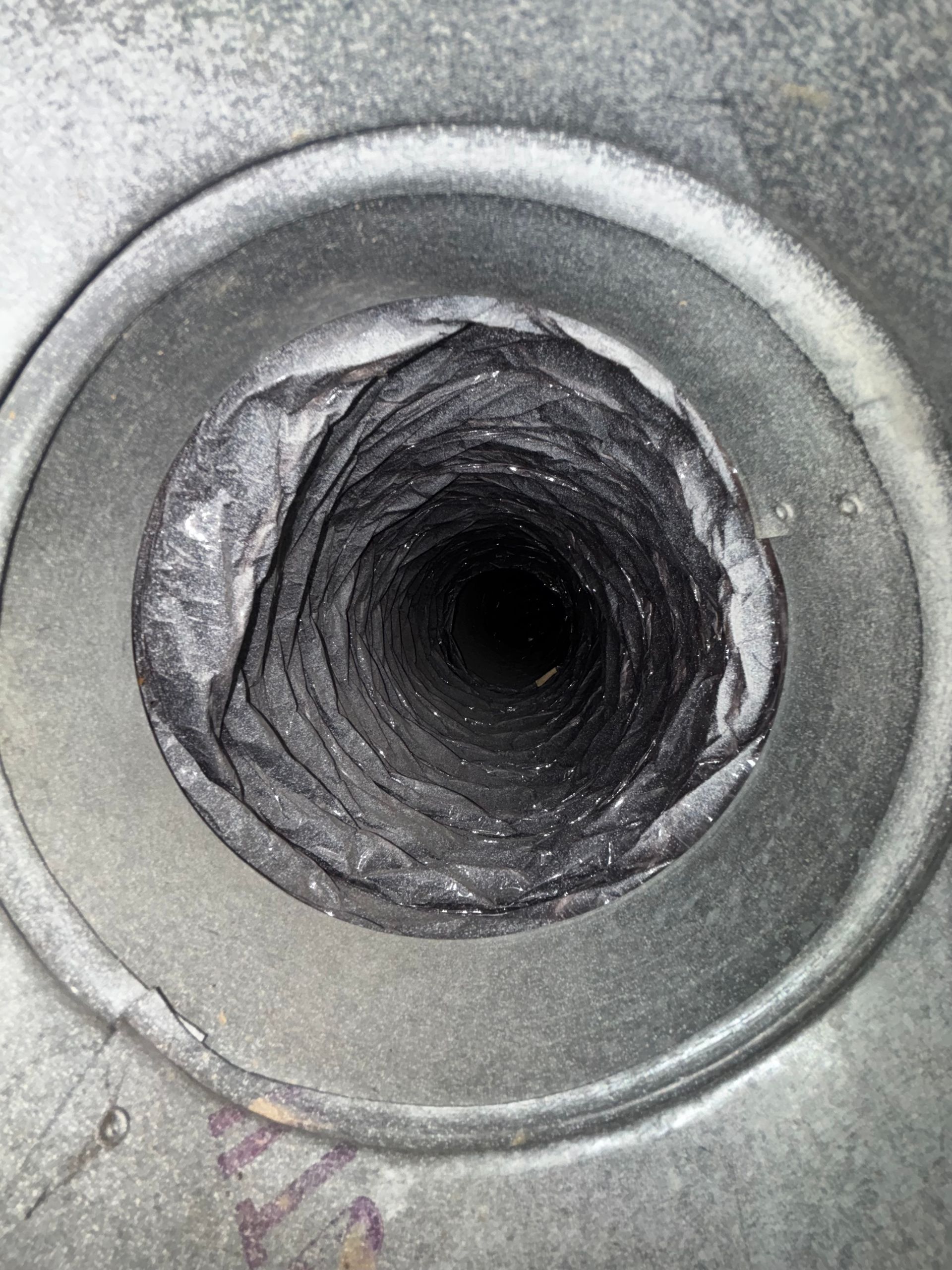 Close-up of a damaged circular metal opening with a dark hollow center