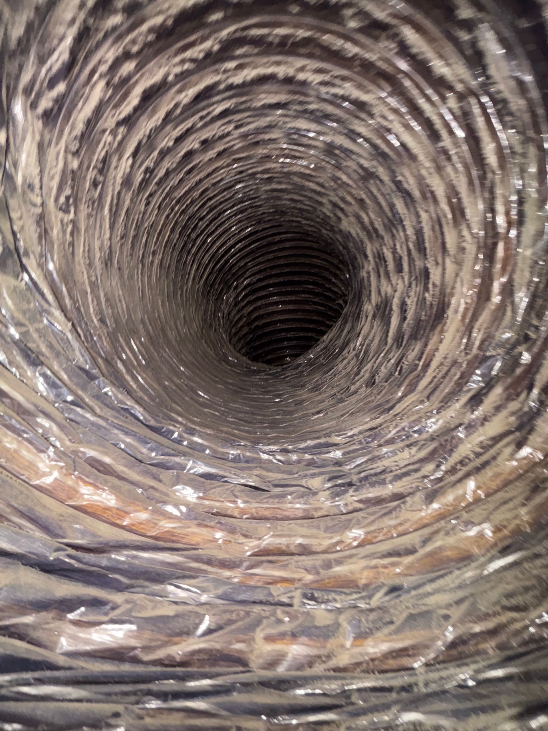 Inside a cylindrical metal pipe with a rough, spiraling interior leading into darkness