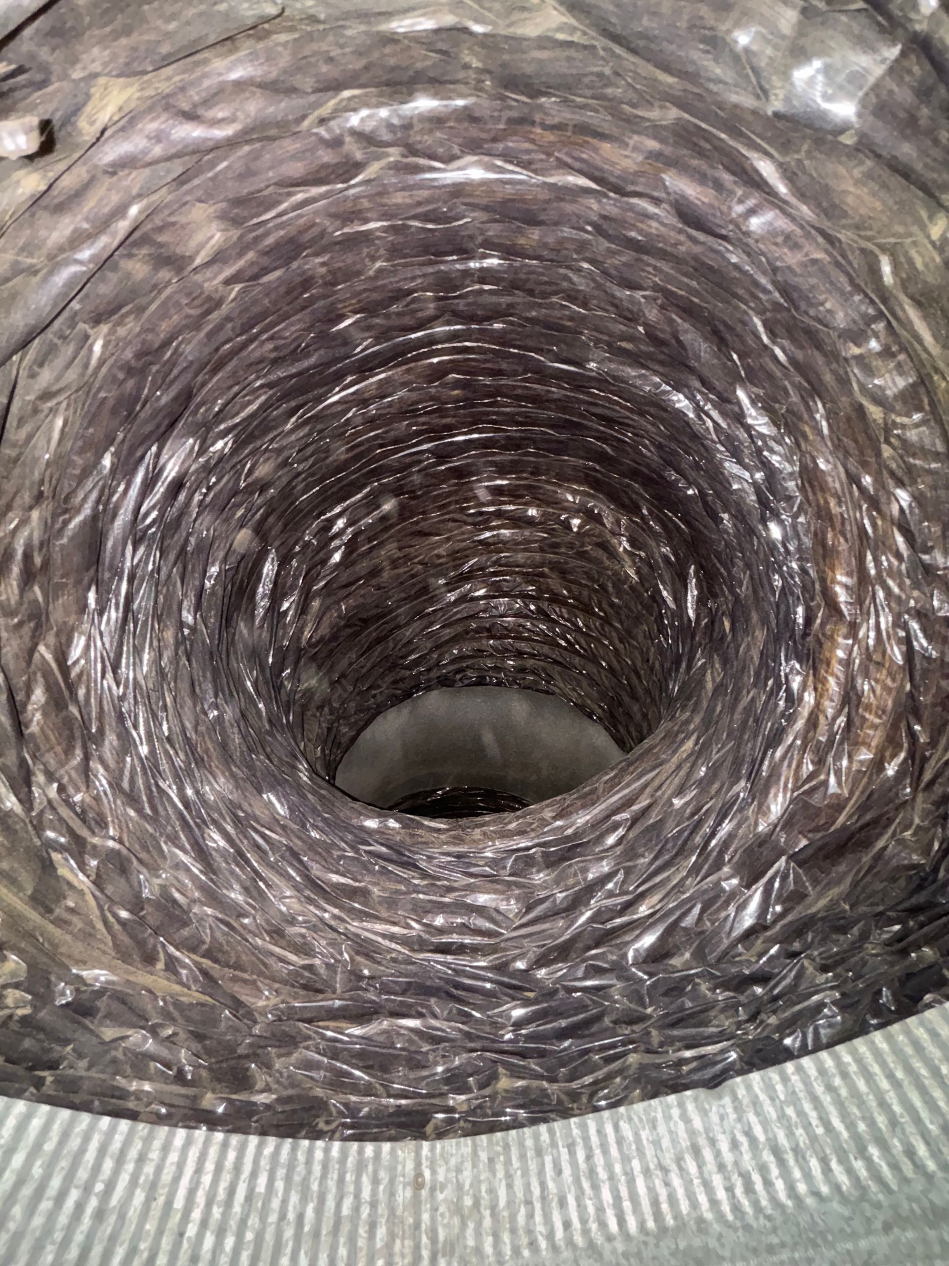 Close-up of a spiraling gray knitted tunnel with a dark hole in the center
