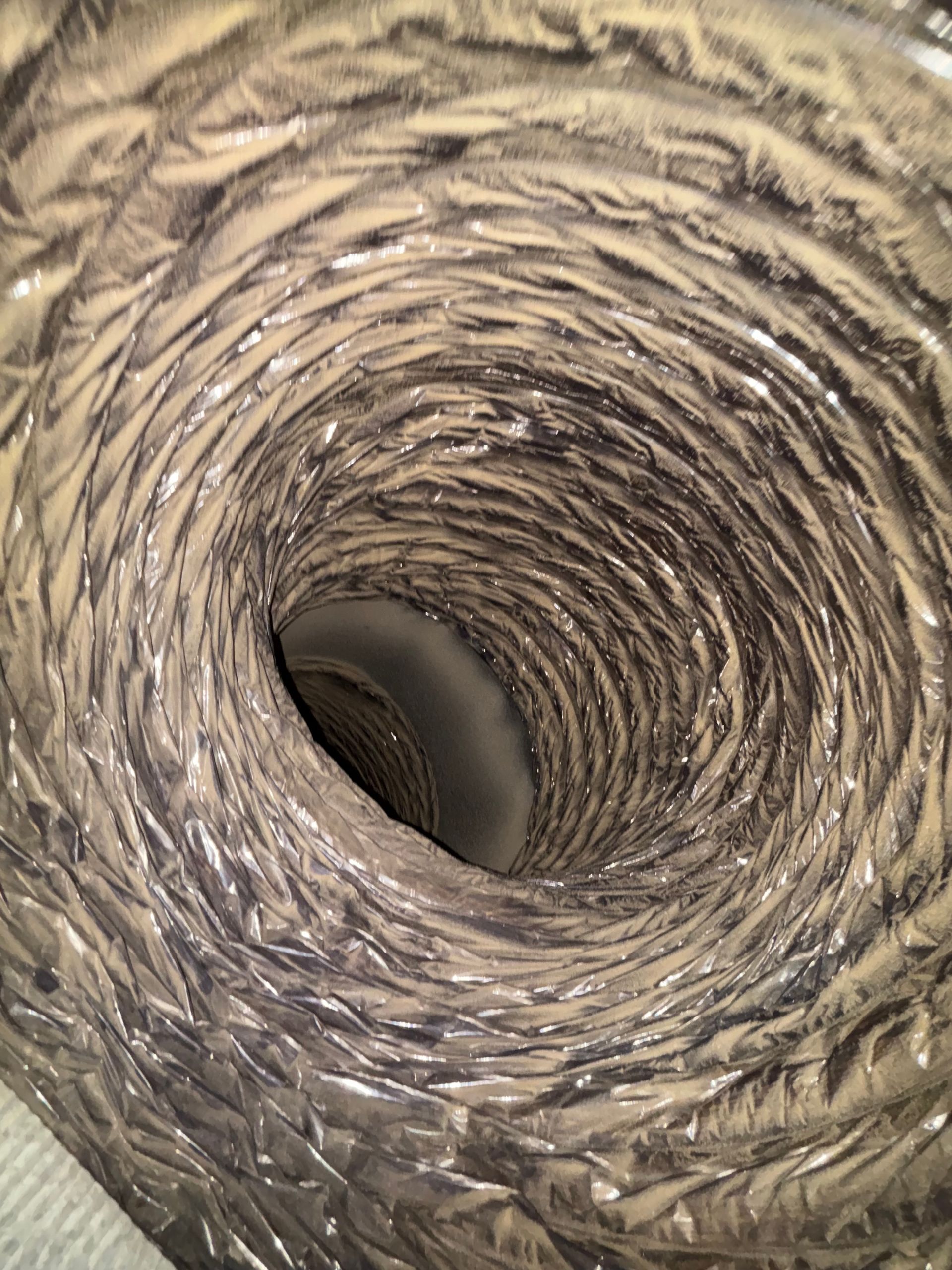 Close-up of a woven cylindrical tunnel with a dark hollow center and tan, textured fibers