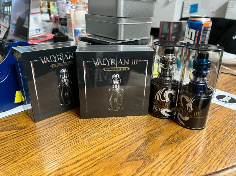 A wooden table topped with boxes of electronic cigarettes and a can of soda.