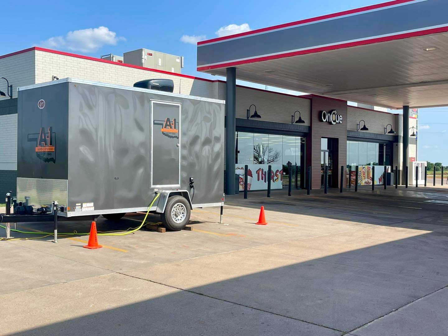 A trailer is parked in front of a gas station.