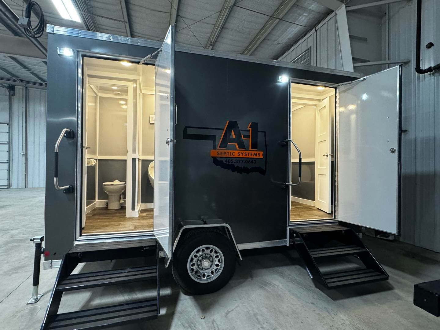 A trailer with a toilet and shower on it is parked in a warehouse.