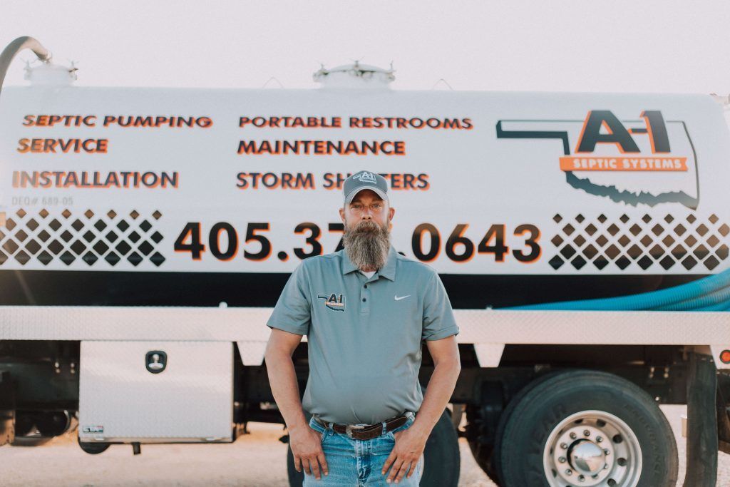 A man is standing in front of a septic pumping truck.