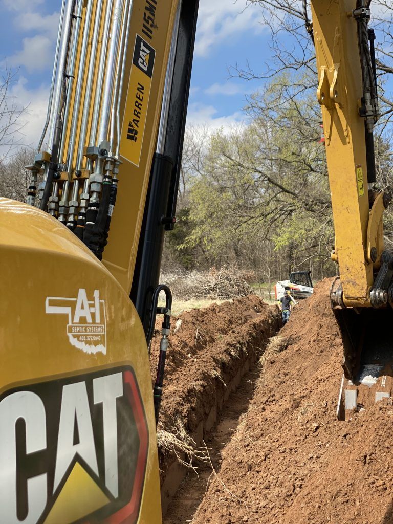 A cat excavator is digging a trench in the dirt.