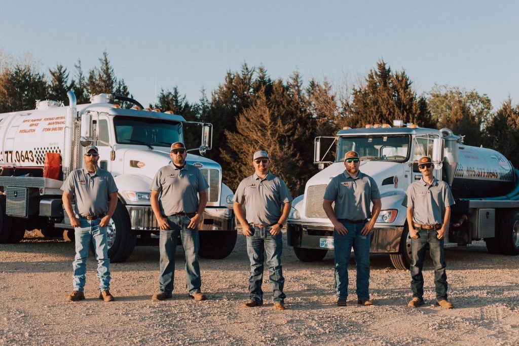 A group of men are standing in front of a row of trucks.