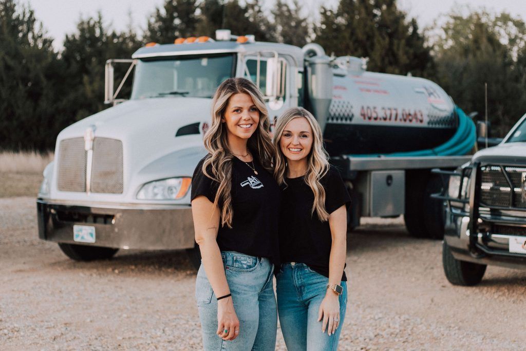 Two women are standing next to each other in front of a truck.
