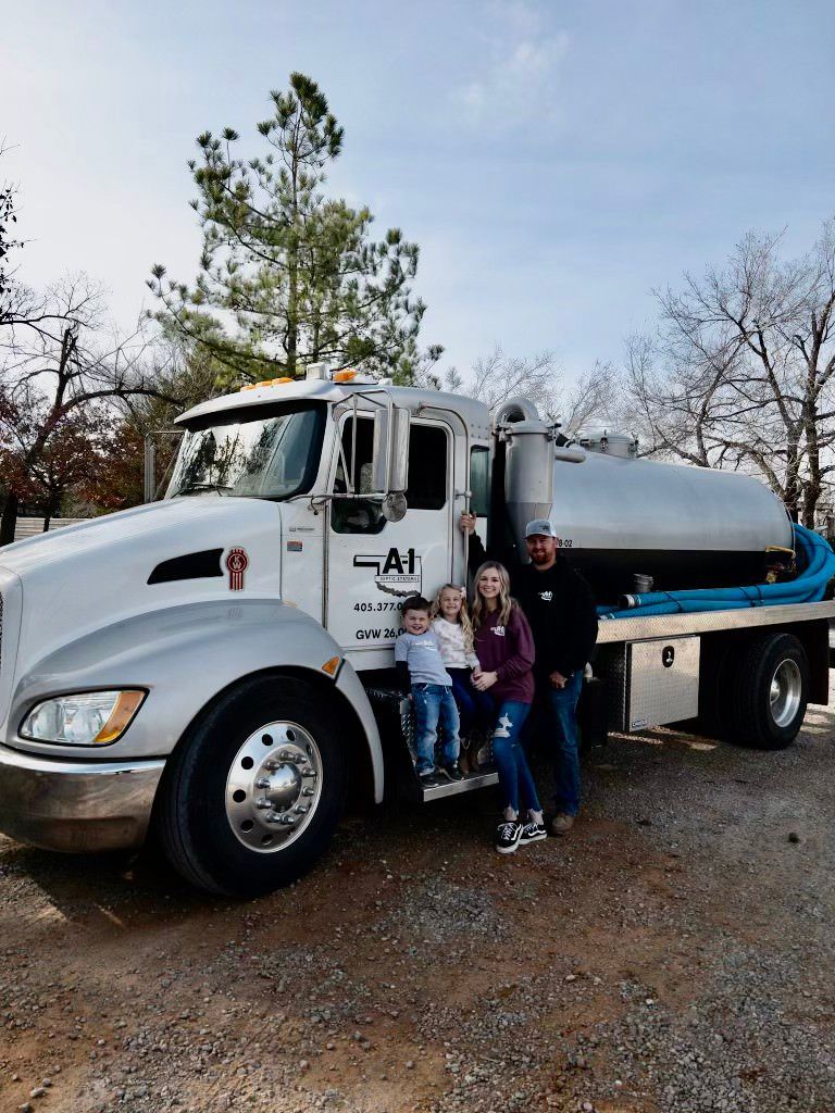 A family is standing in front of a vacuum truck.