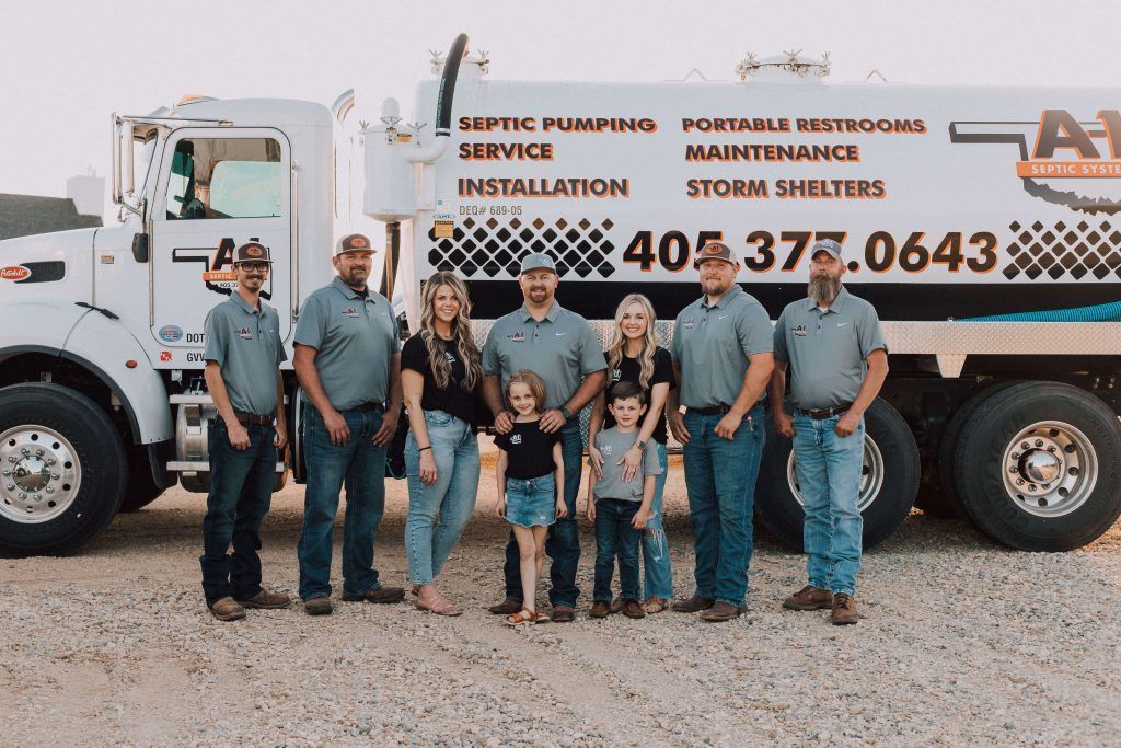 A group of people standing in front of a septic pumping truck.