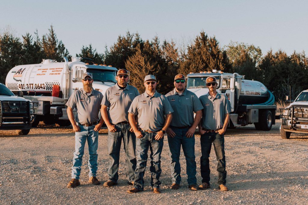 A group of men are posing for a picture in front of trucks.